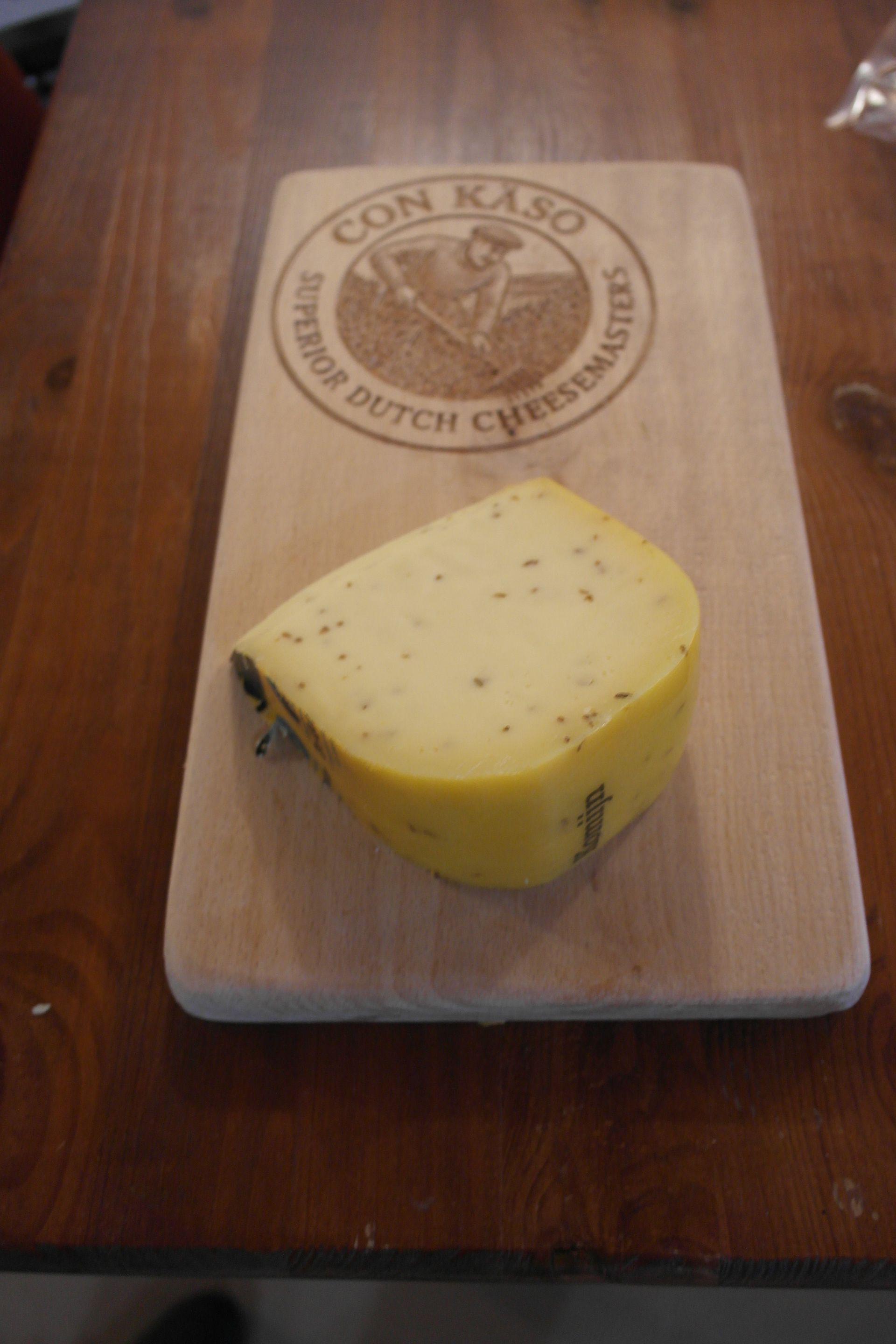 Runder Käse „De Gelder“ mit angeschnittenem Keil, gelber Rinde und Logo obenauf.