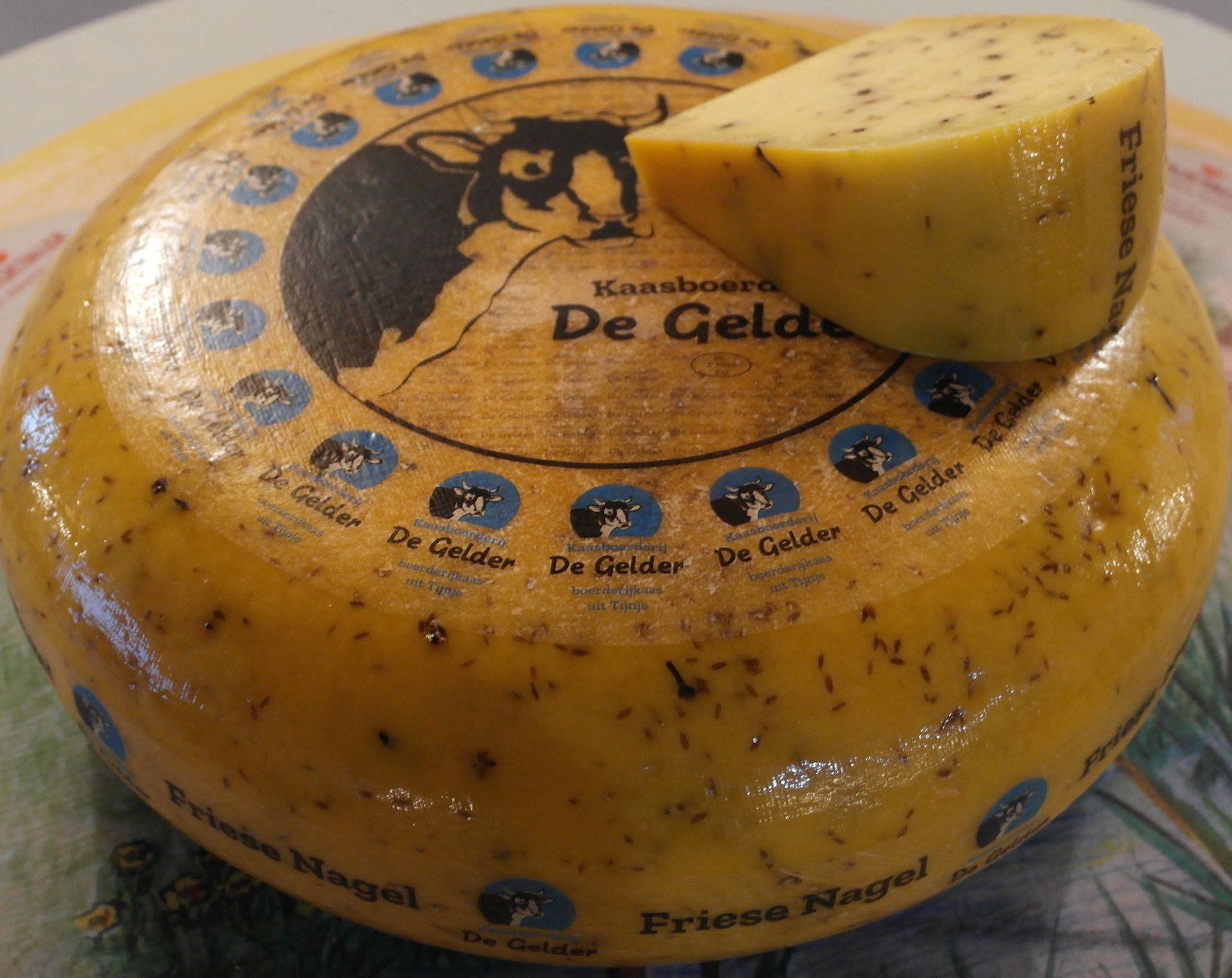 Runder Käselaib, „De Gelder“, mit einem ausgeschnittenen Stück; goldbraun mit Kräutern.