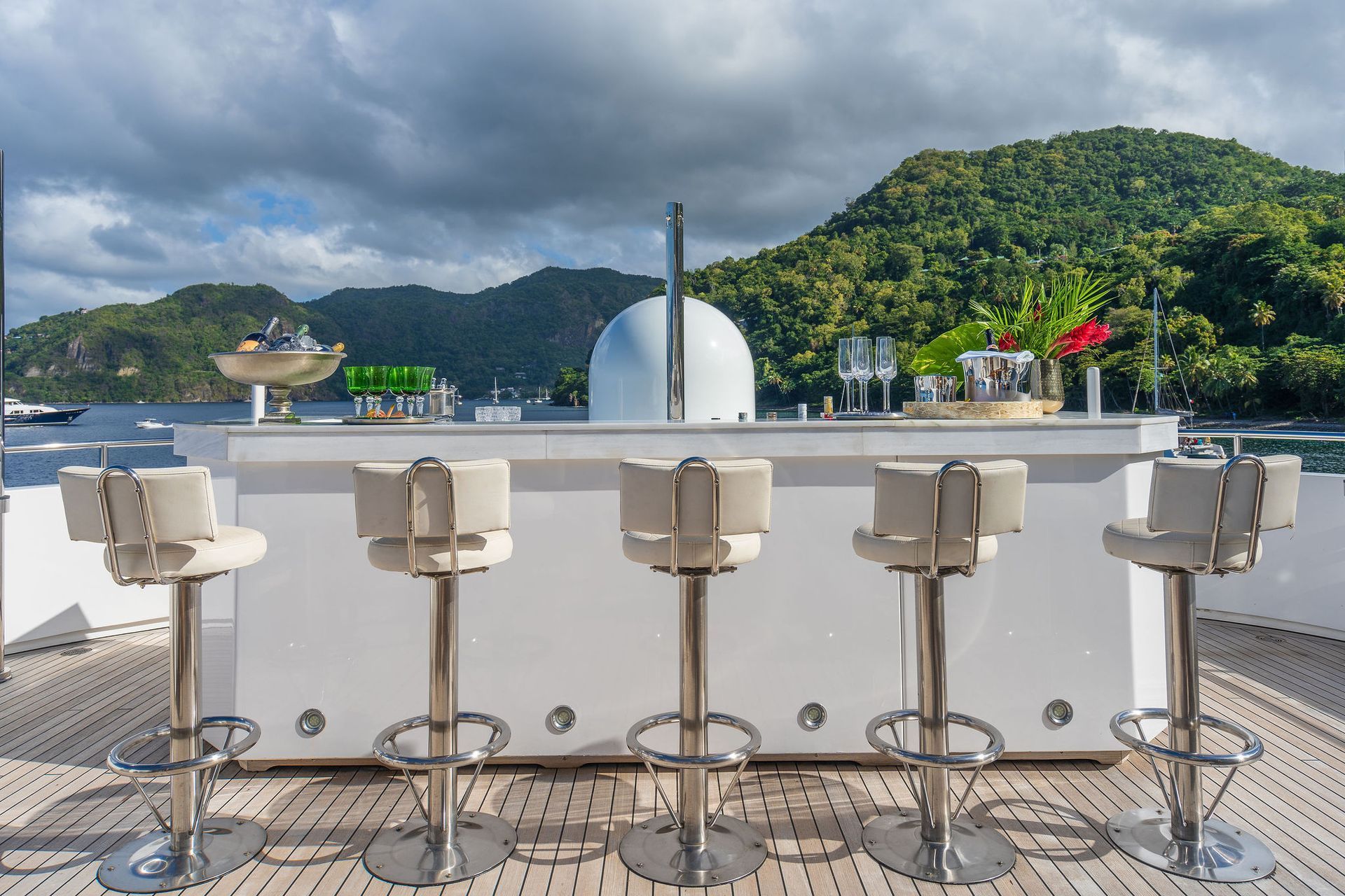 a bar with stools on a yacht with mountains in the background