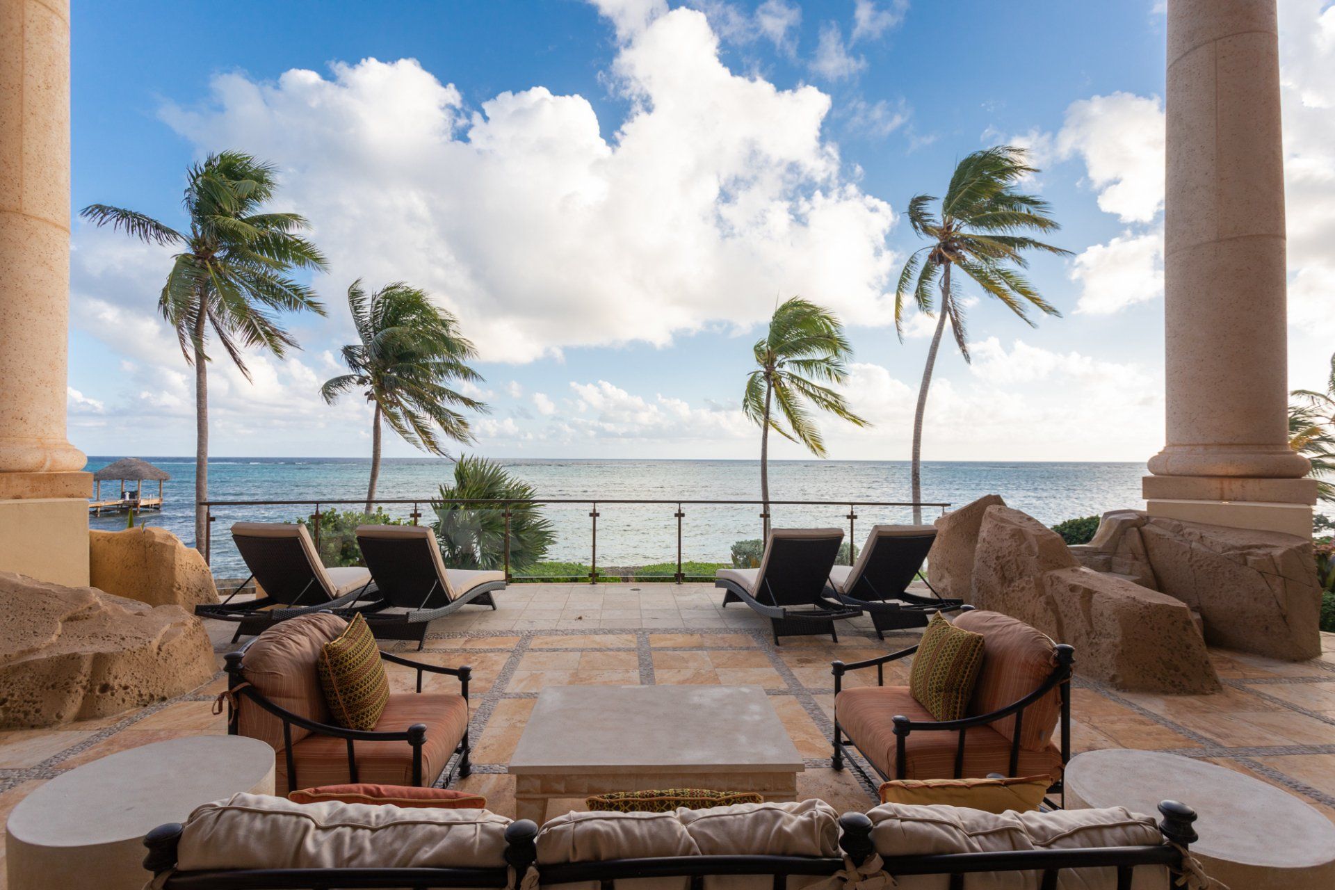 a patio with a view of the ocean and palm trees