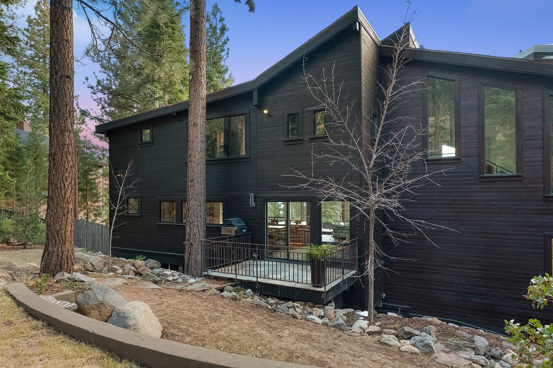 a large black house is surrounded by trees and rocks