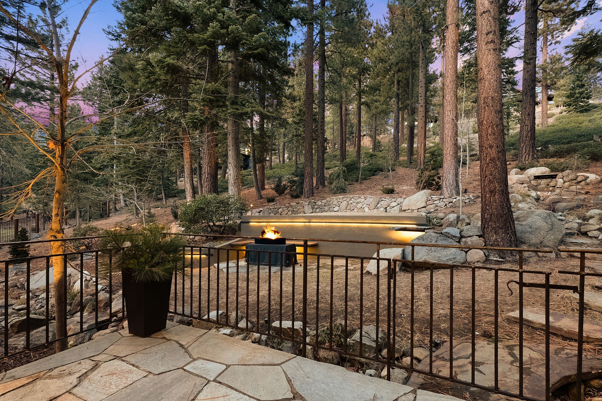 a patio with a wrought iron railing overlooking a forest