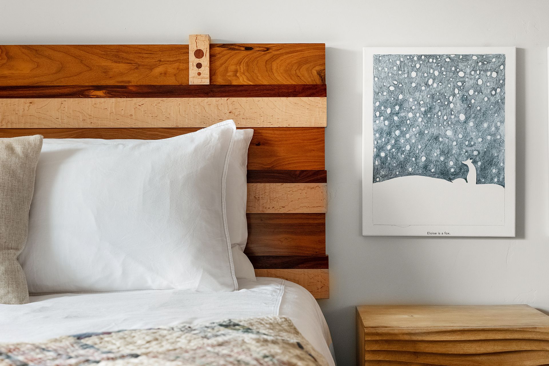 a bed with a wooden headboard and a painting on the wall above it