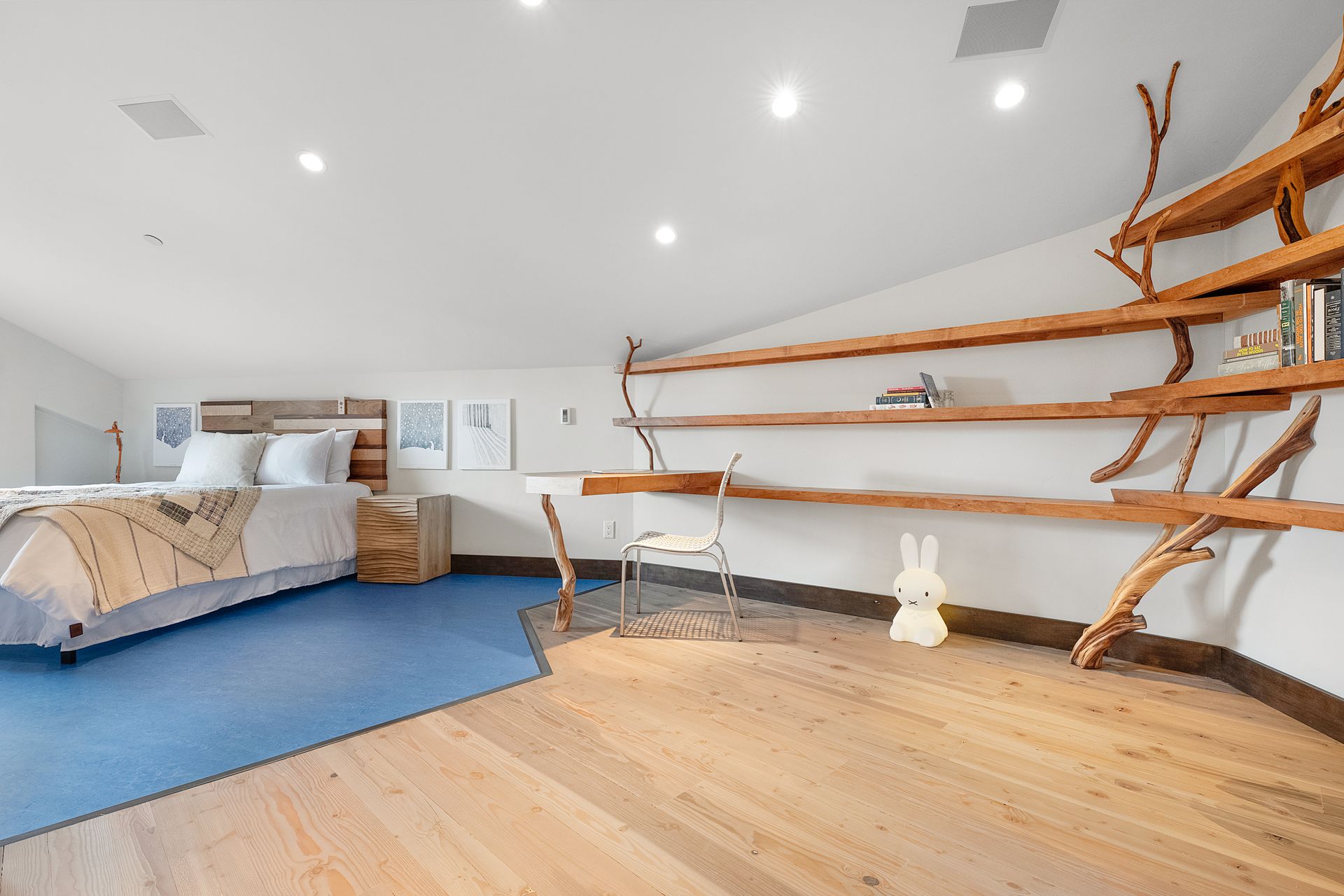 a bedroom with a bed, desk, shelves and a blue rug