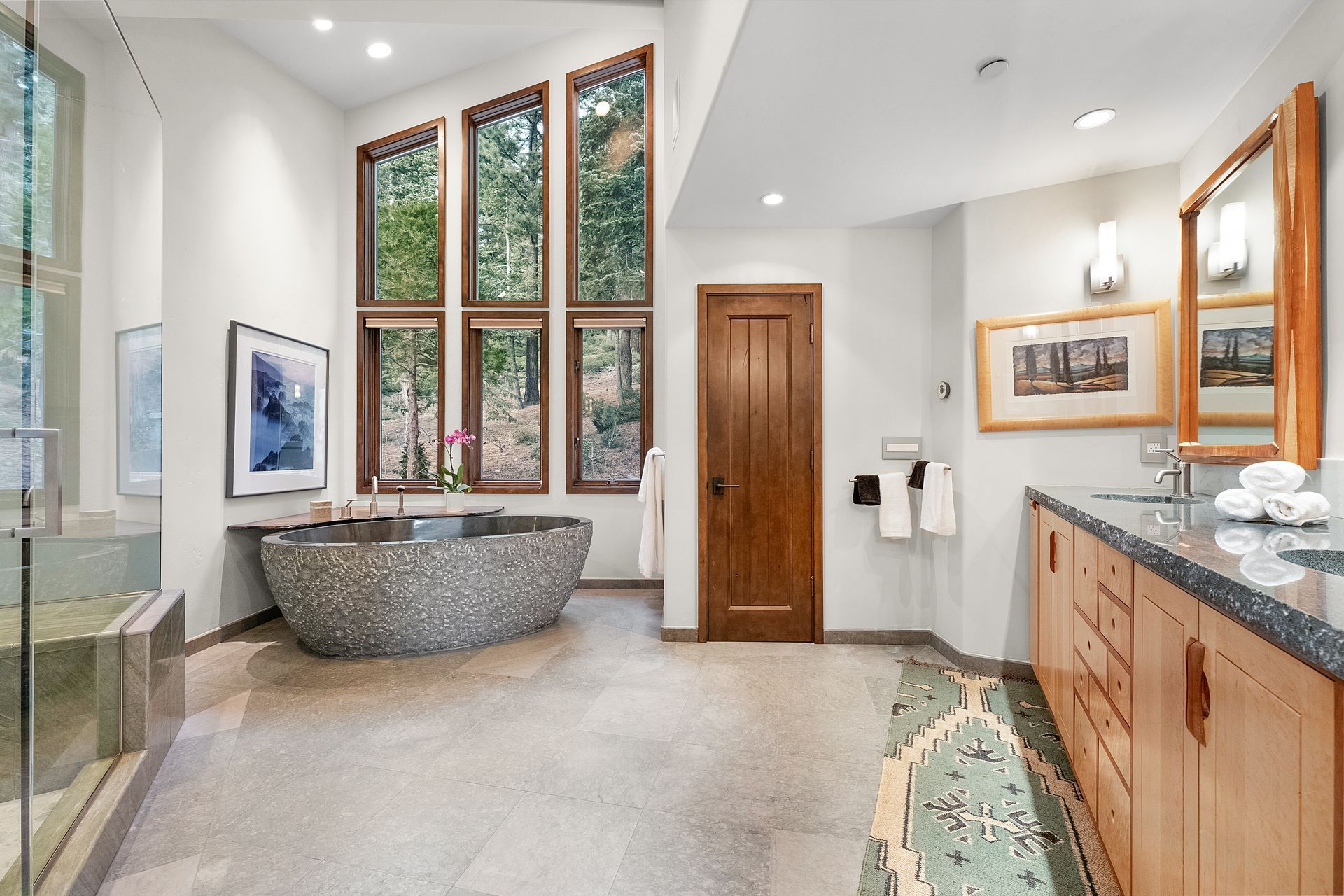 a bathroom with a bathtub, sinks, mirrors and lots of windows