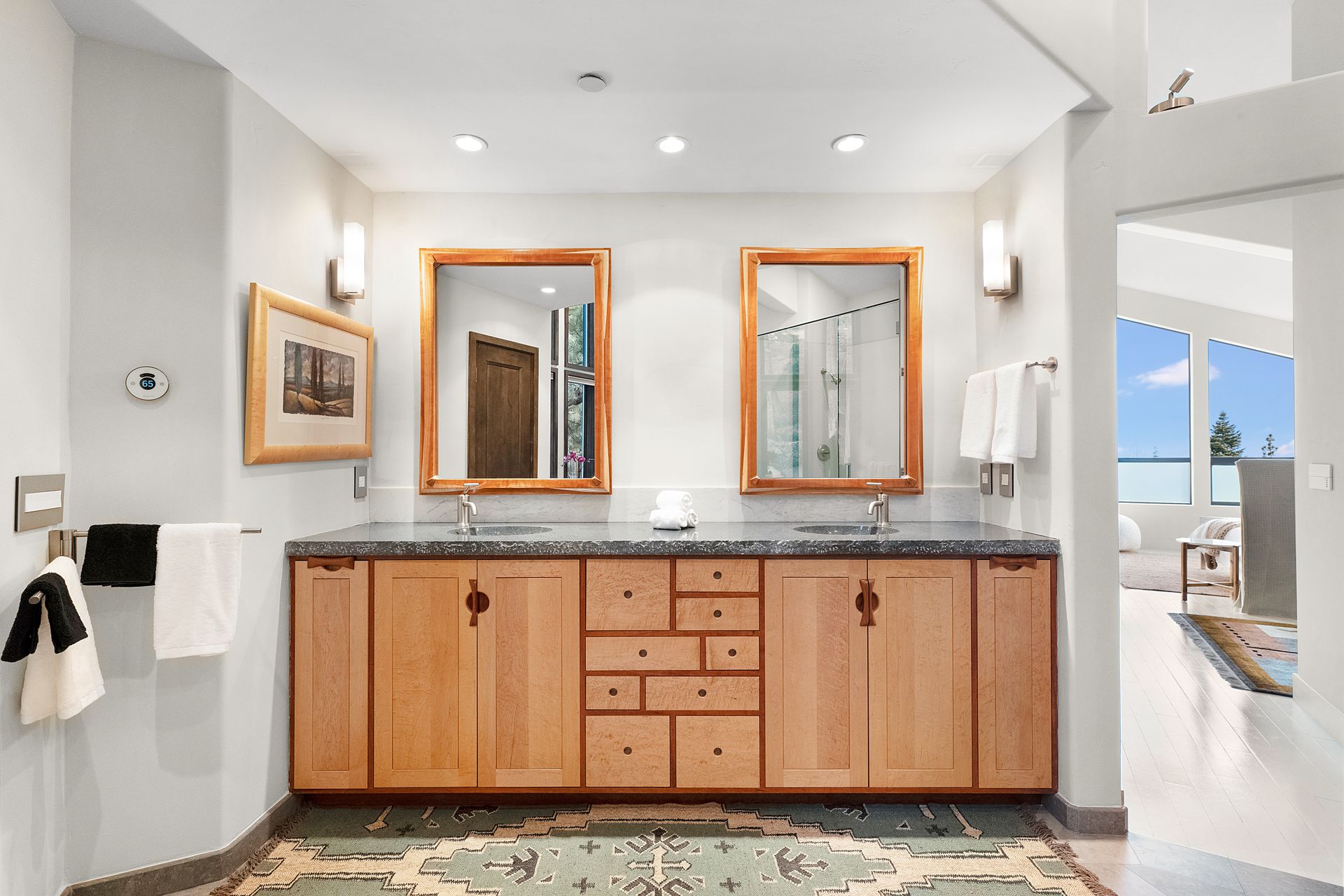 a bathroom with two sinks, two mirrors and wooden cabinets