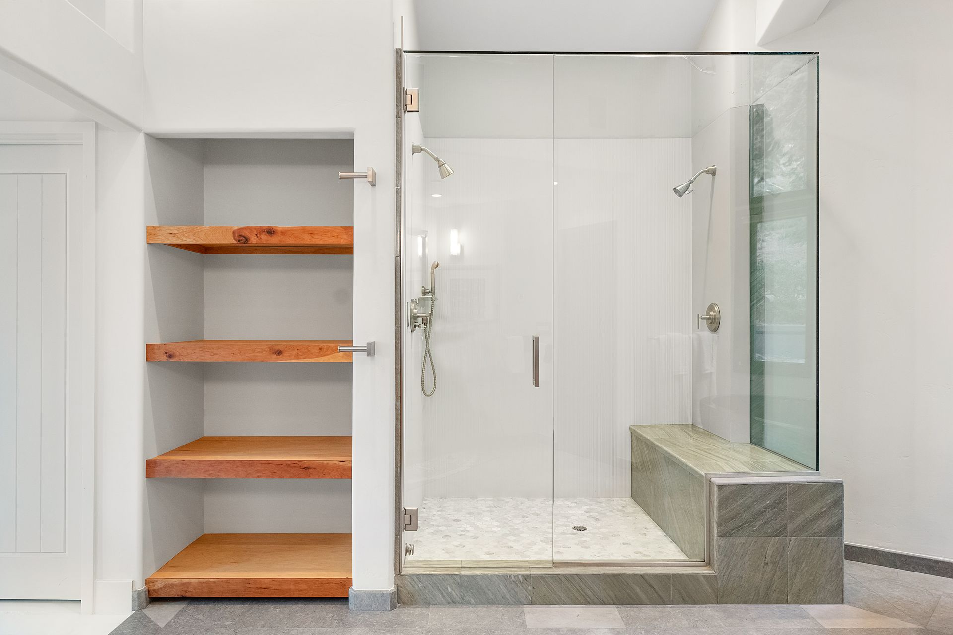 a bathroom with a walk in shower and wooden shelves