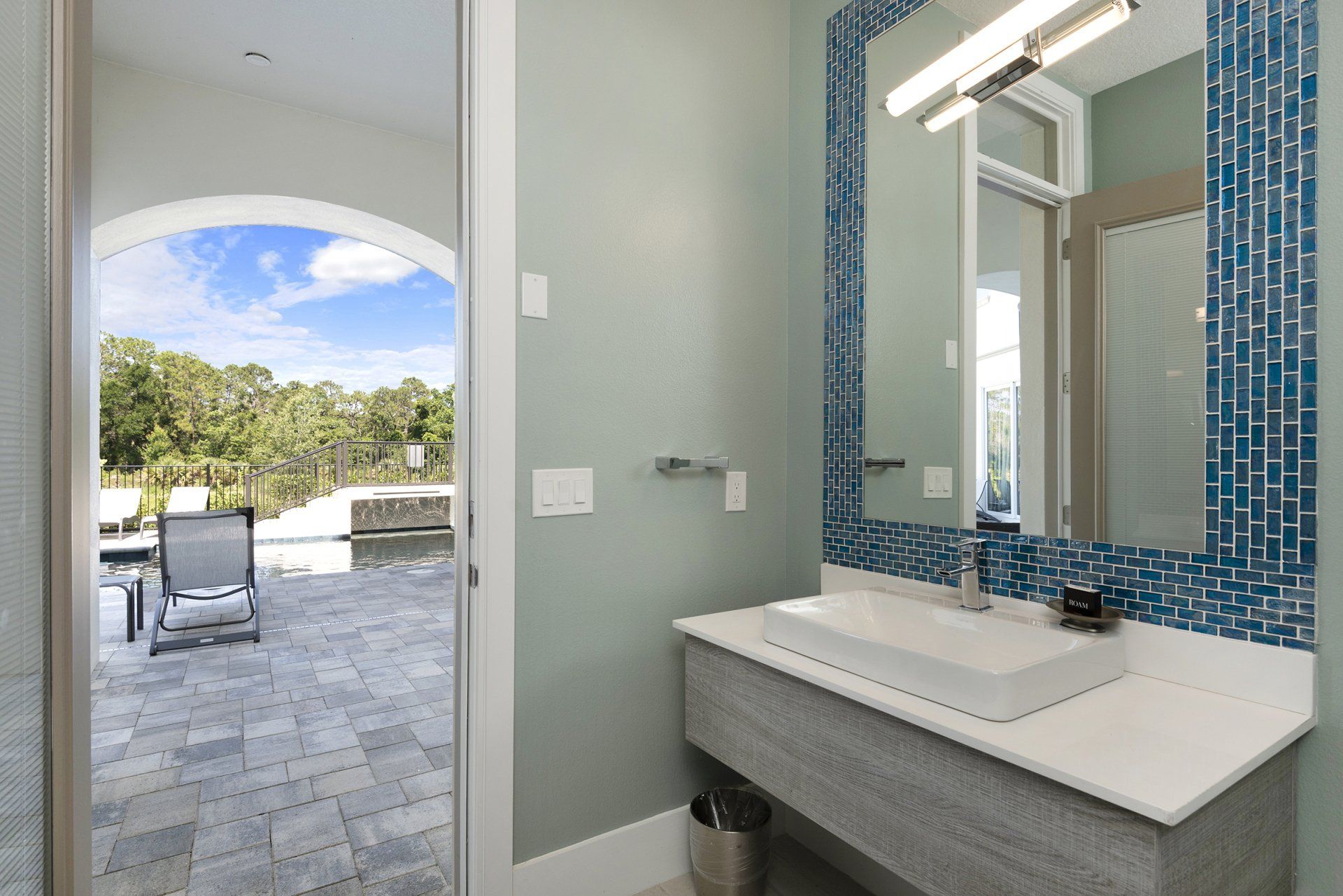 a bathroom with a sink and a mirror and a view of a patio