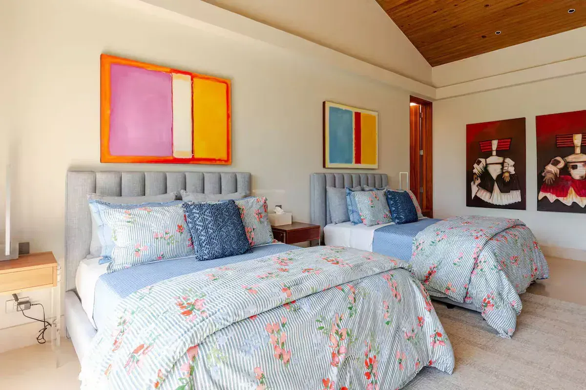 a bedroom with two beds, a chair, a dresser and a television