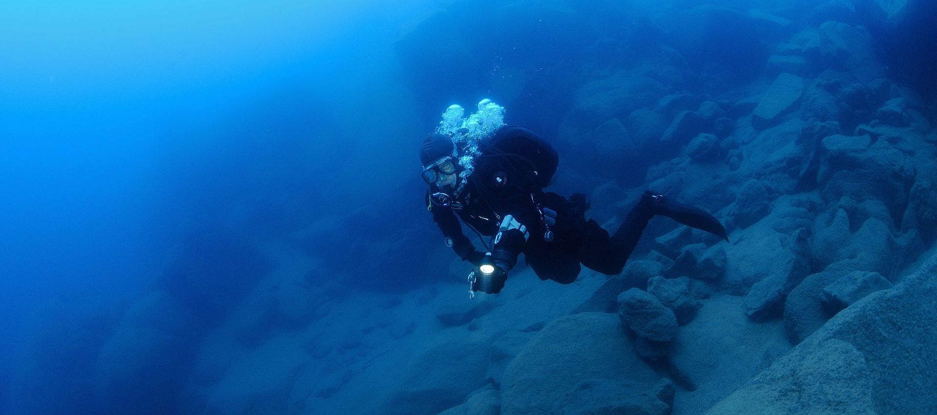 A scuba diver is swimming in the ocean near a coral reef.