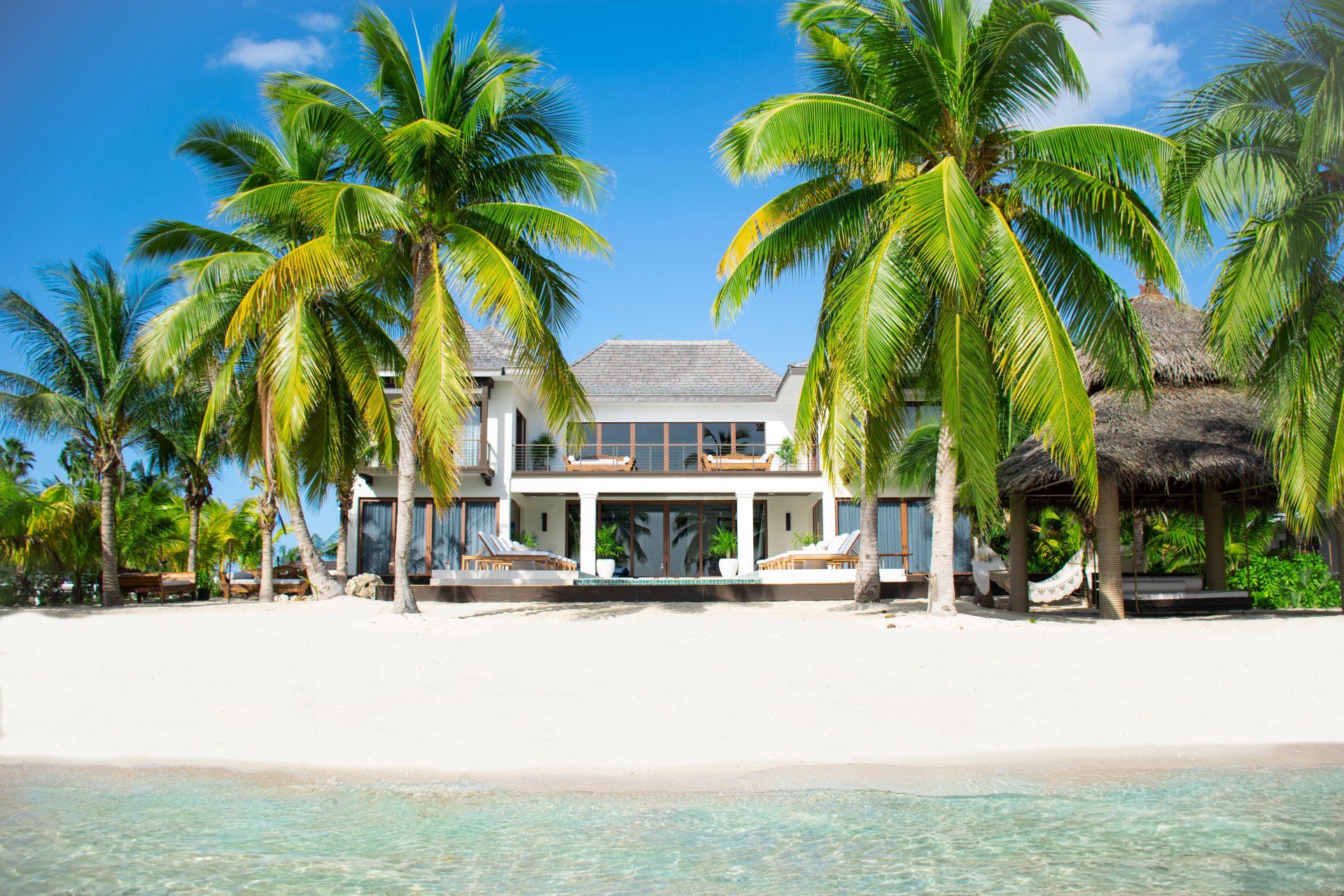 there is a large house on the beach surrounded by palm trees