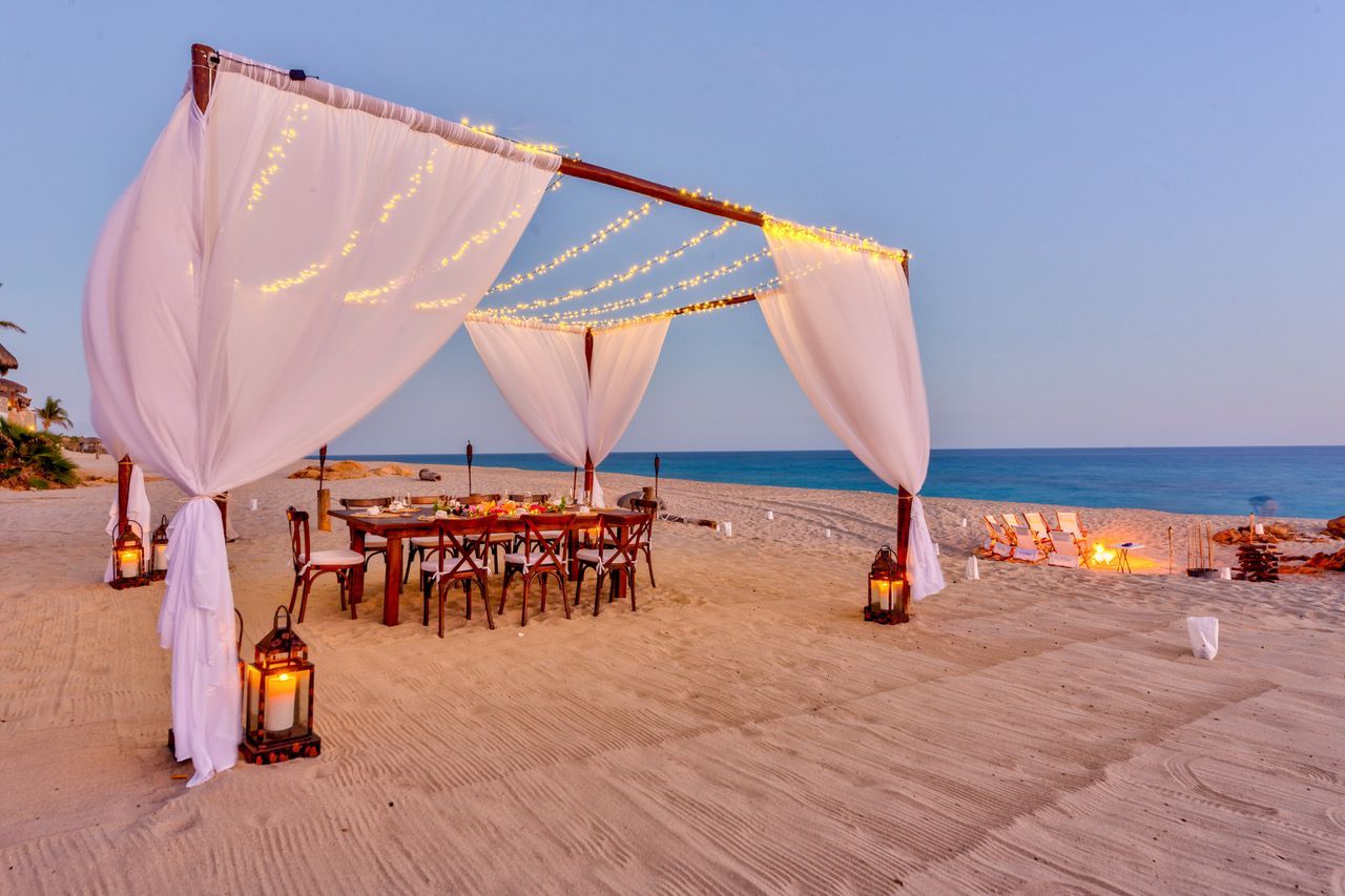 there is a table and chairs under a canopy on the beach