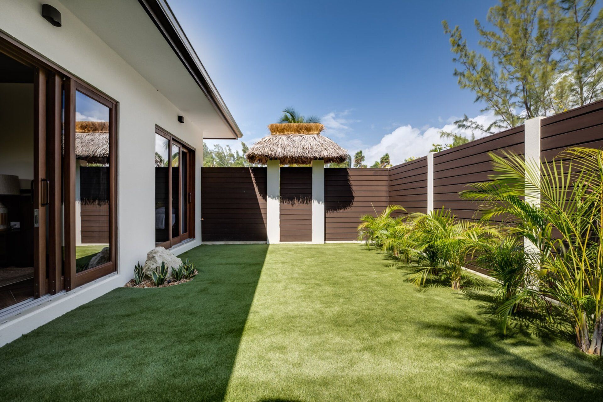 the backyard of a house with a lush green lawn and a wooden fence
