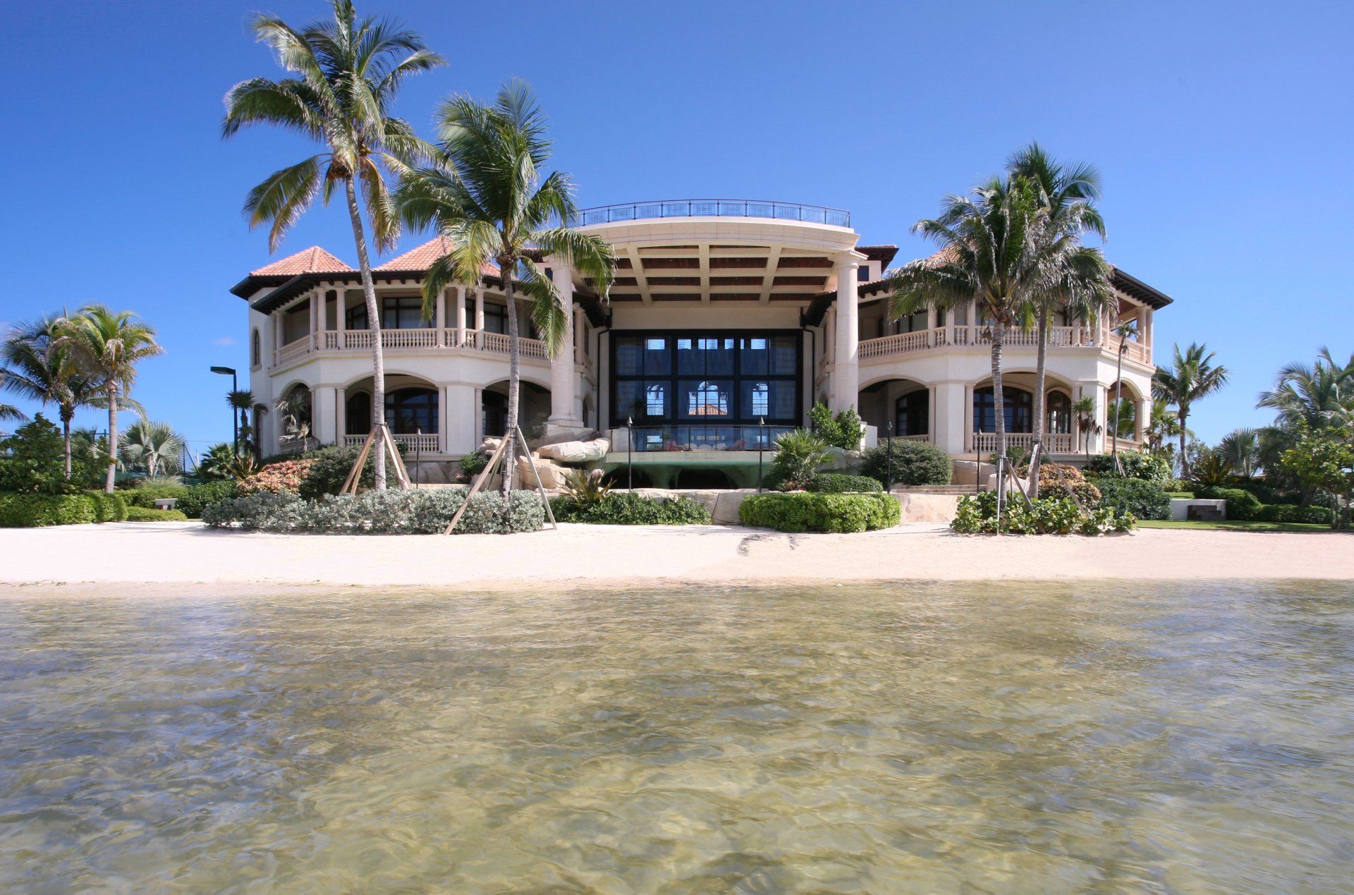 a large house on a beach with palm trees in front of it