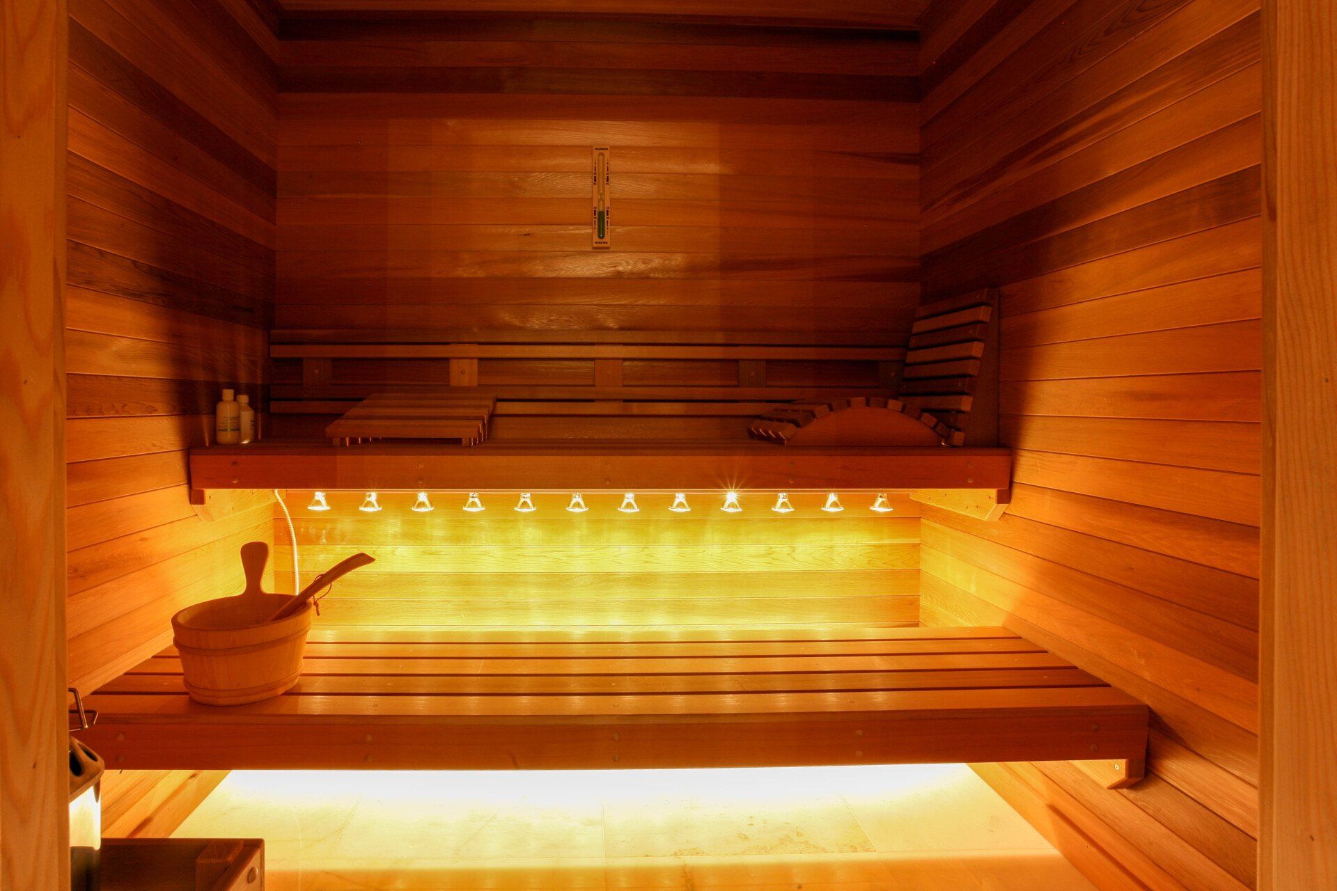 a wooden sauna with lights on the walls and a bucket on the bench