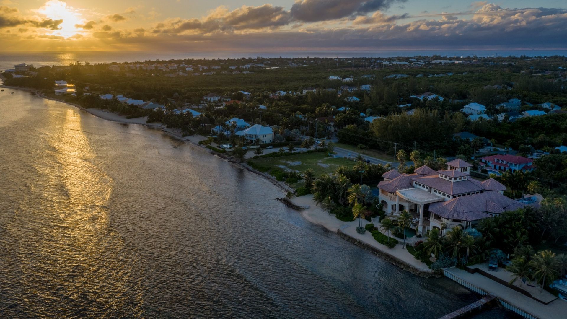 An aerial view of a house in the middle of a body of water at sunset.