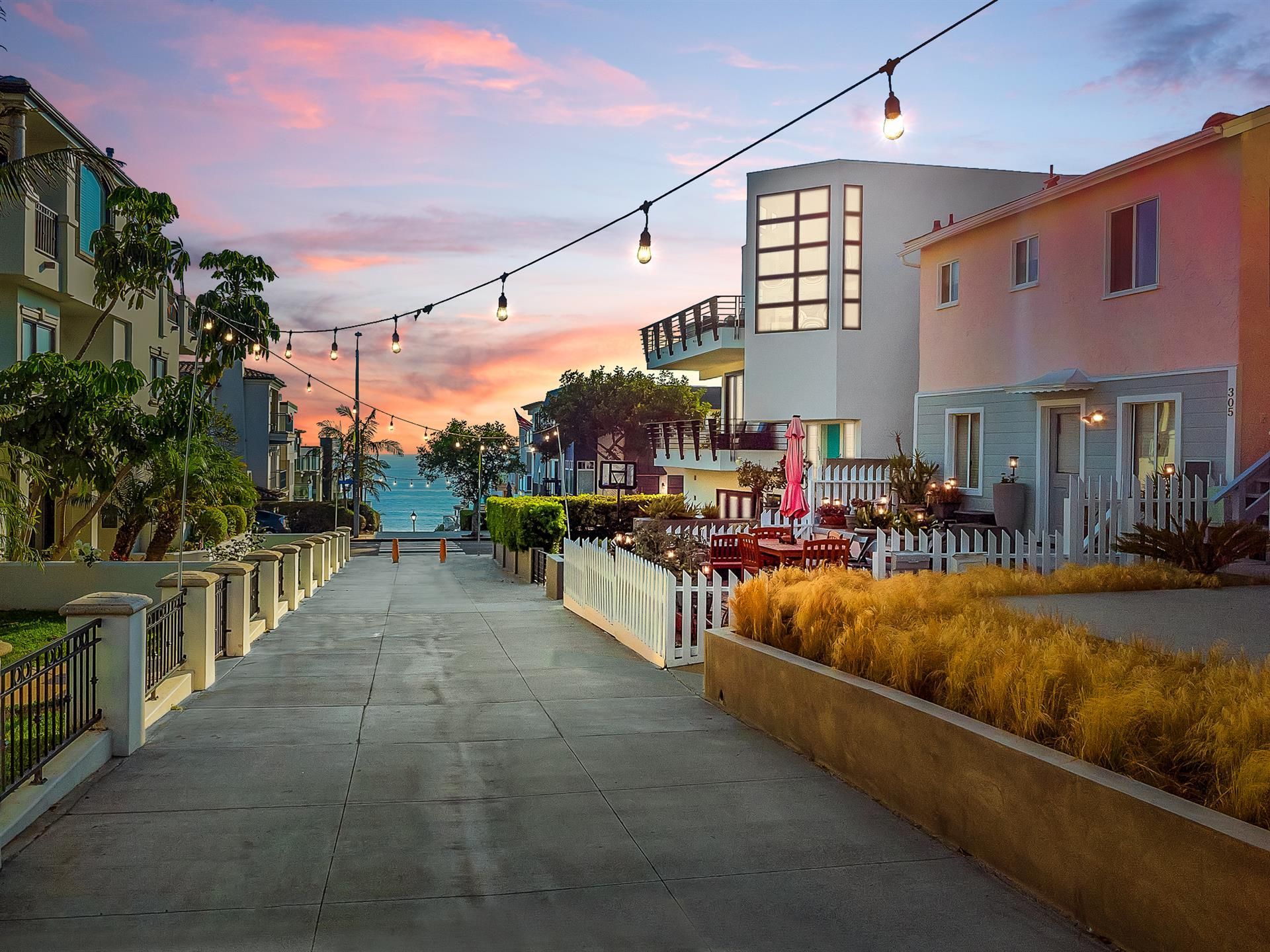 A row of houses along a street with a sunset in the background.