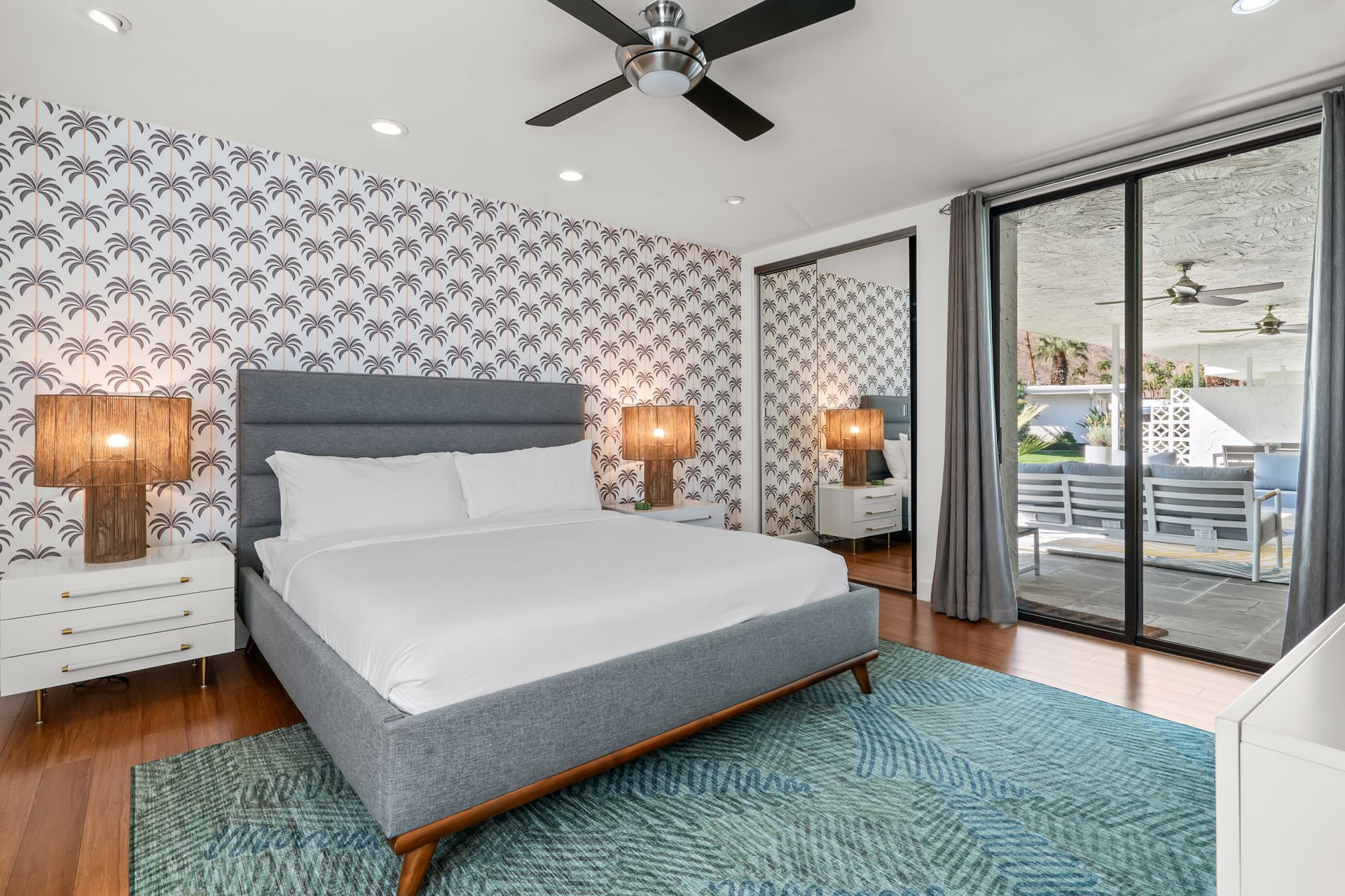 a bedroom with a king size bed, sliding glass doors, a large mirror and a ceiling fan