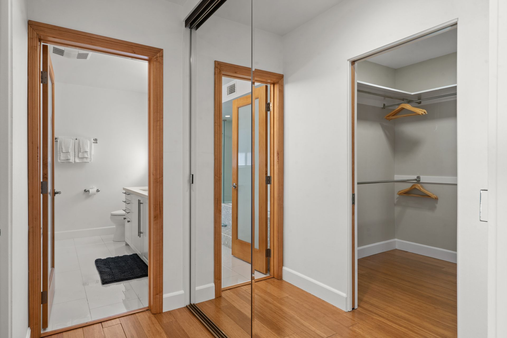 a walk in closet with a mirror between two doors and a bathroom