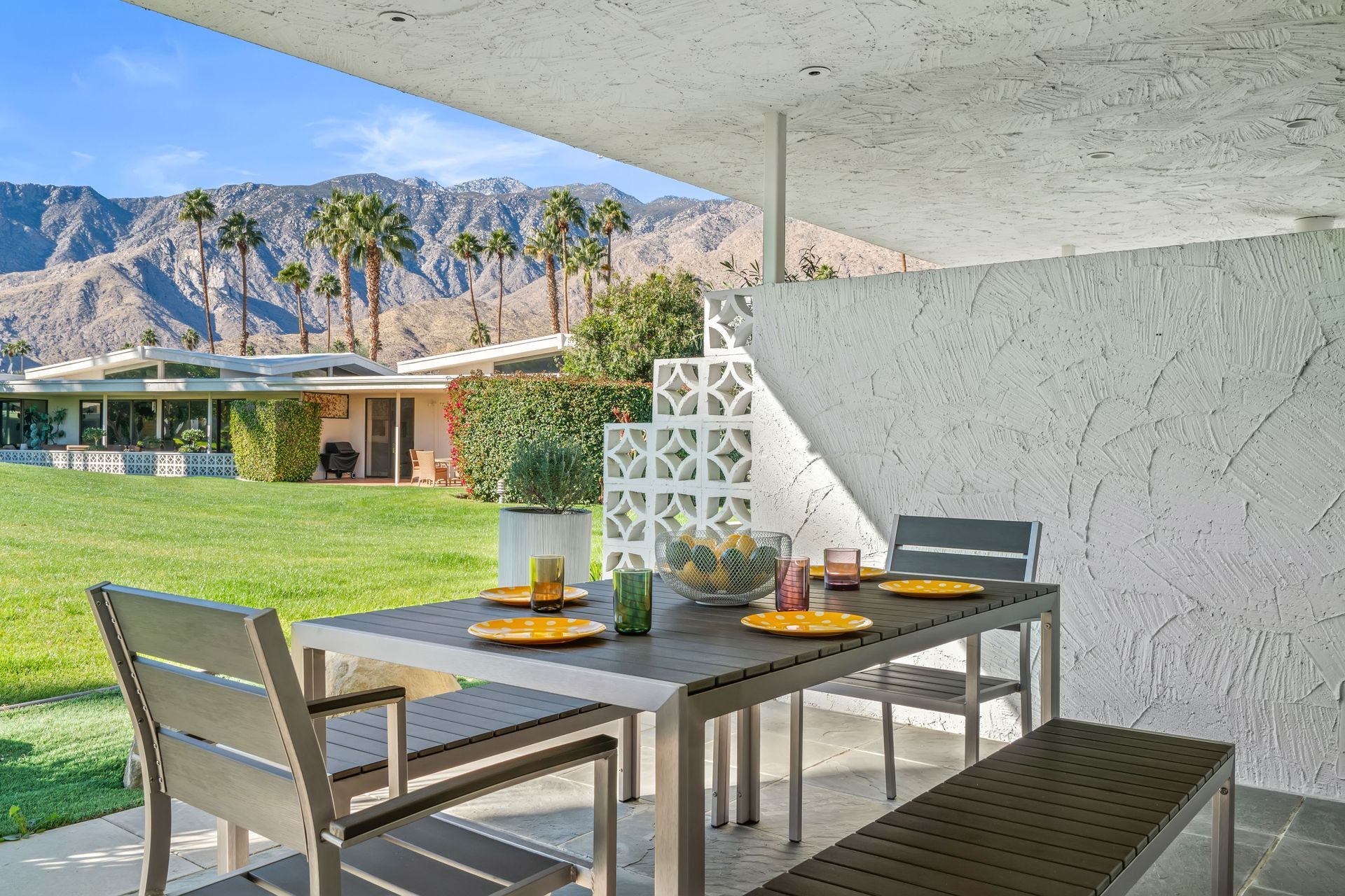 a table and chairs on a patio with mountains in the background
