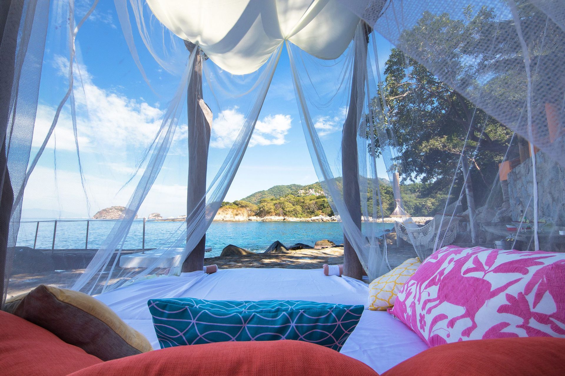 a bed with a canopy over it looking out over the ocean