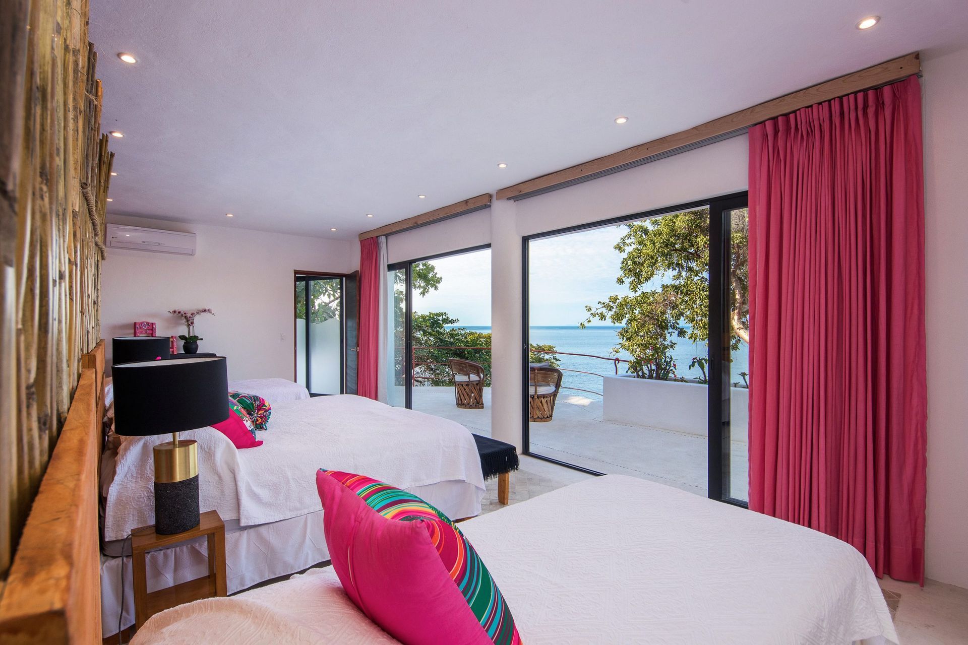 a bedroom with two beds and a balcony overlooking the ocean