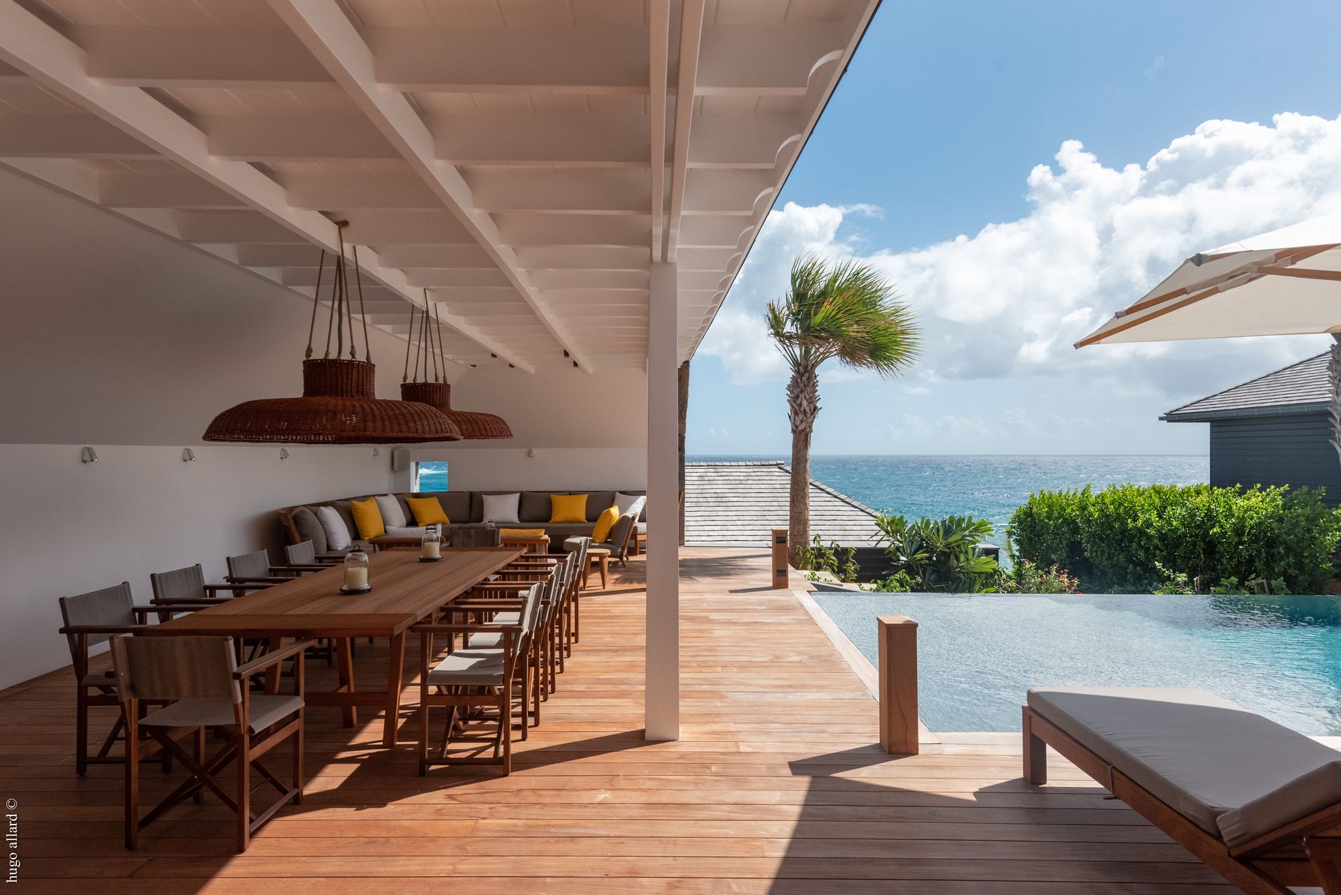 a large wooden deck with a table and chairs overlooking the ocean