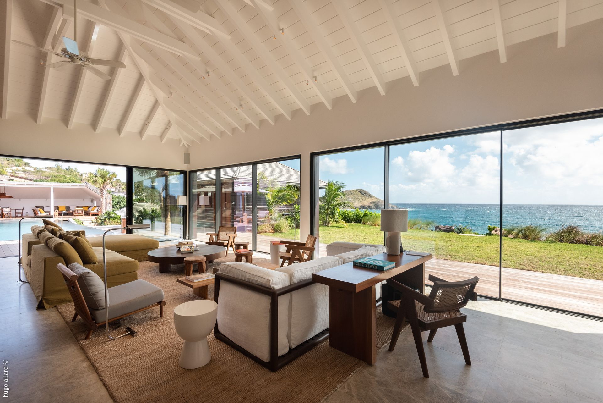 a living room with a desk, couch, chairs and a view of the ocean