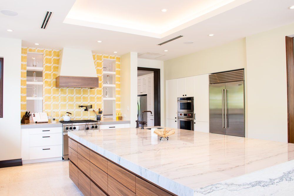 A kitchen with a large island in the middle of it and stainless steel appliances.