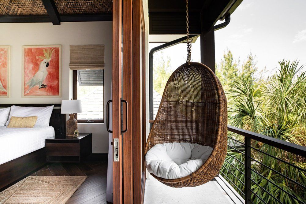 a wicker chair is hanging from a balcony next to a bedroom