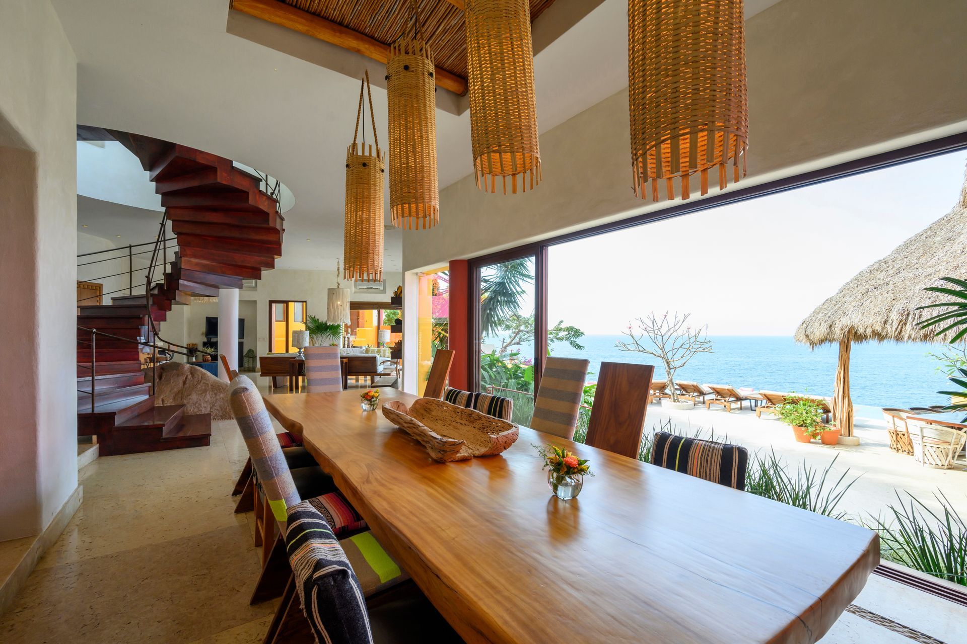 a dining room with a long wooden table and chairs and a view of the ocean