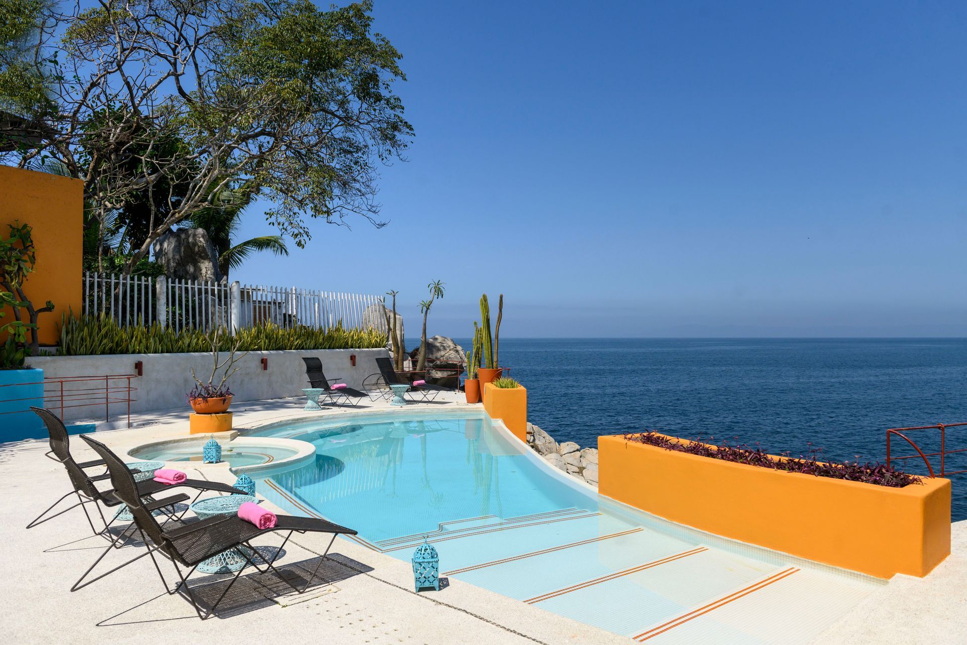 a large swimming pool surrounded by chairs overlooking the ocean