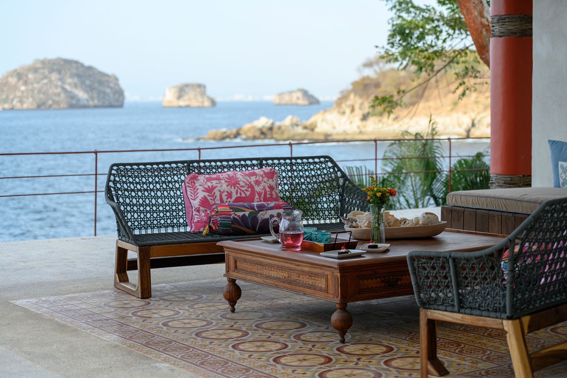 a patio with a couch, chairs and a coffee table overlooking the ocean