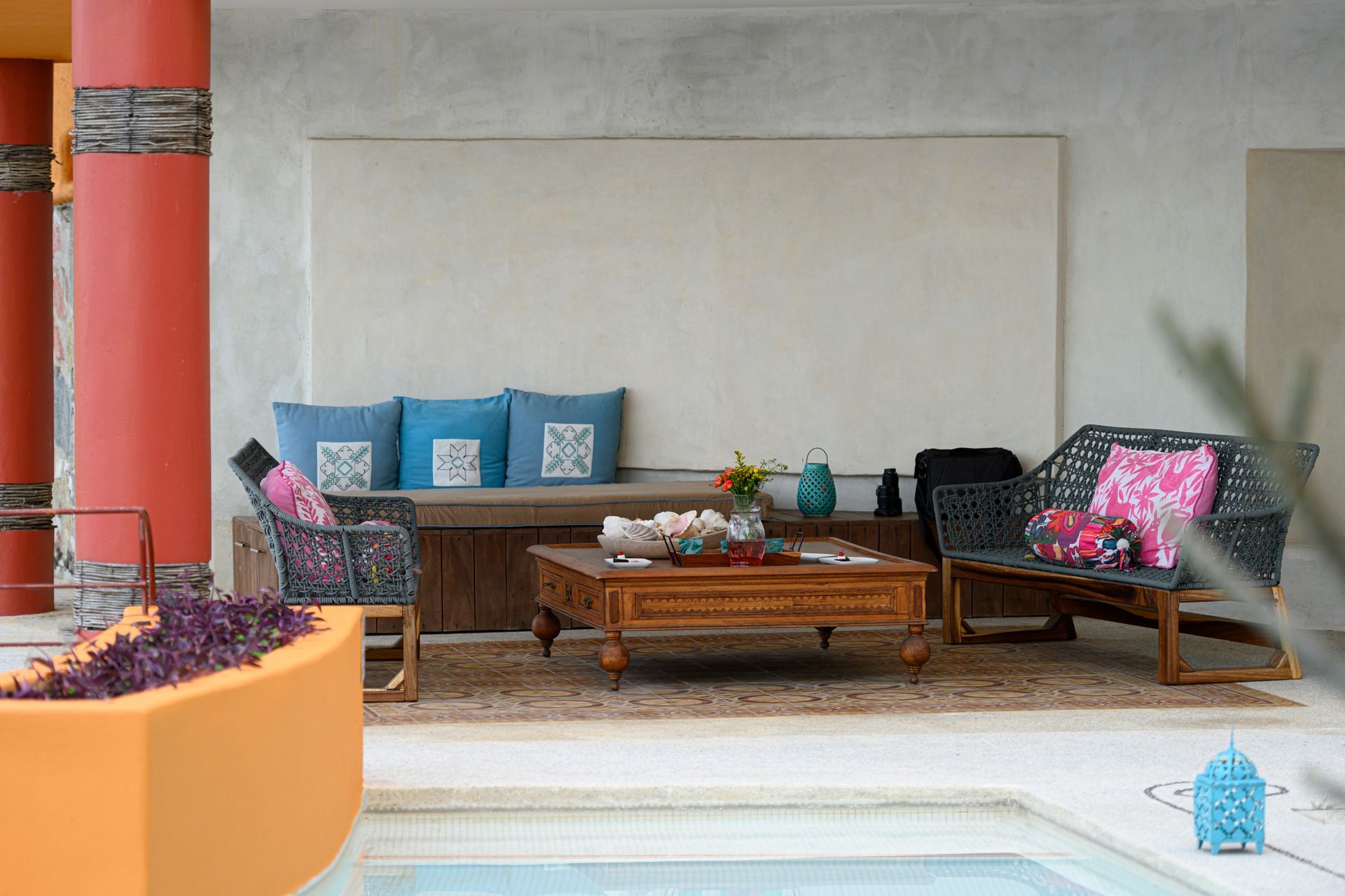 a living room with a couch, table and chairs next to a pool