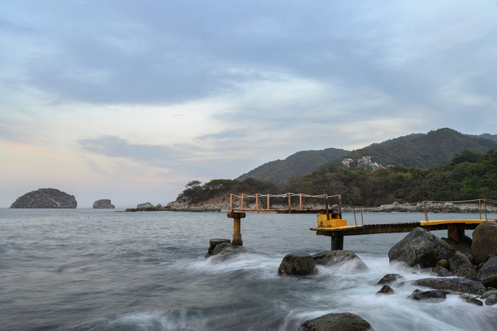 a dock in the middle of the ocean with mountains in the background