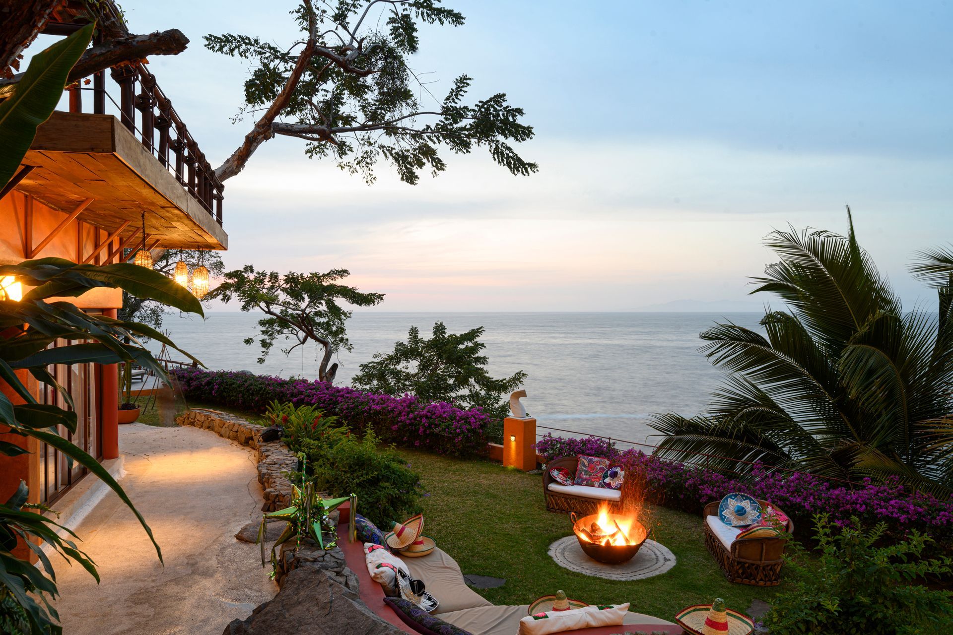 a fire pit in the middle of a lush green yard overlooking the ocean