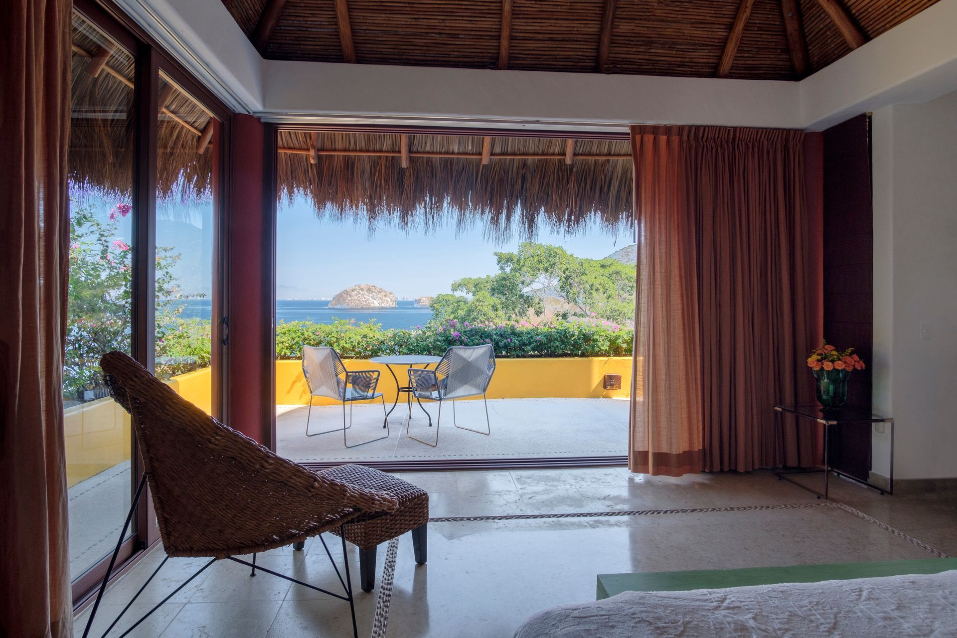 a bedroom with a thatched roof and a view of the ocean