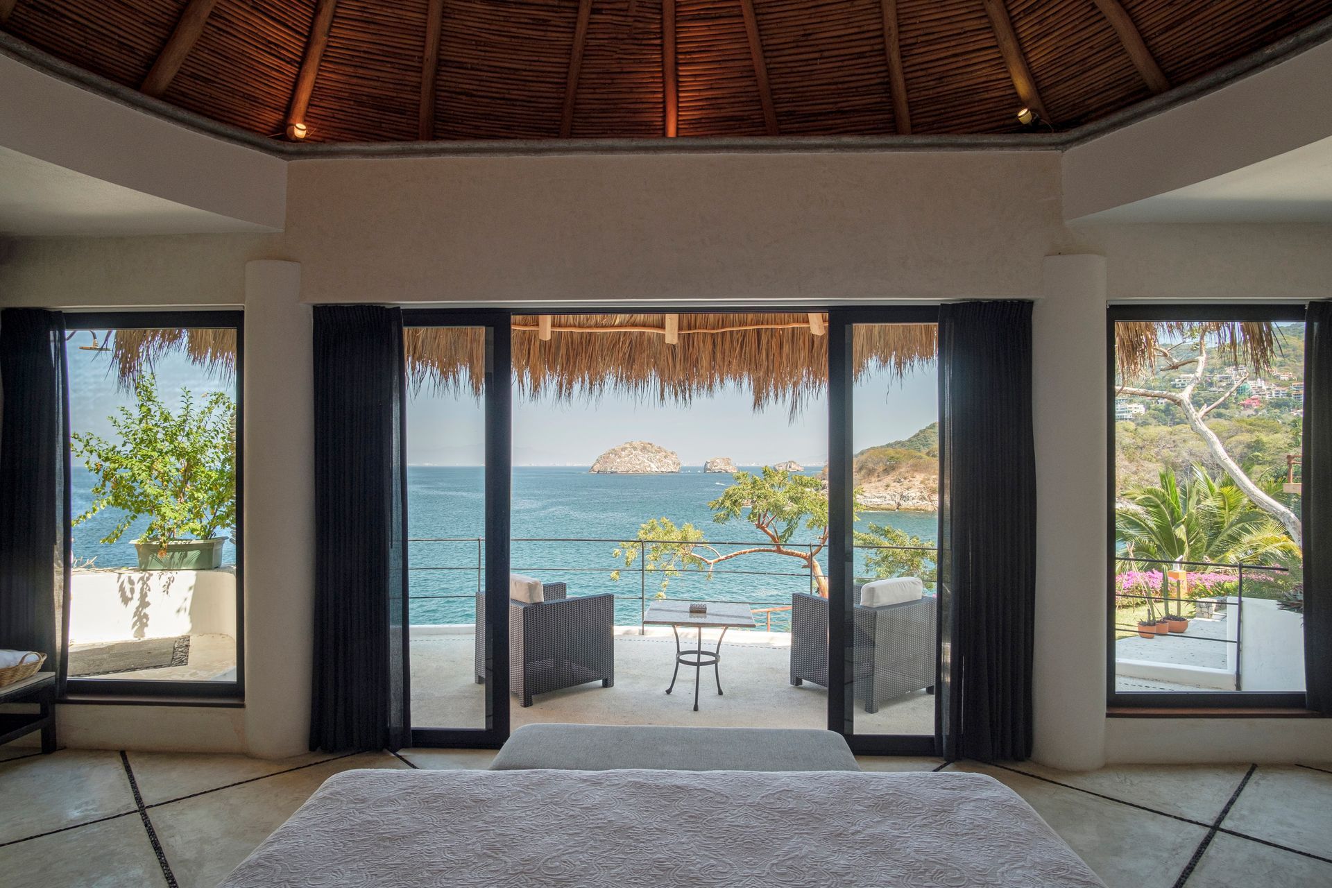 a bedroom with sliding glass doors leading to a balcony overlooking the ocean