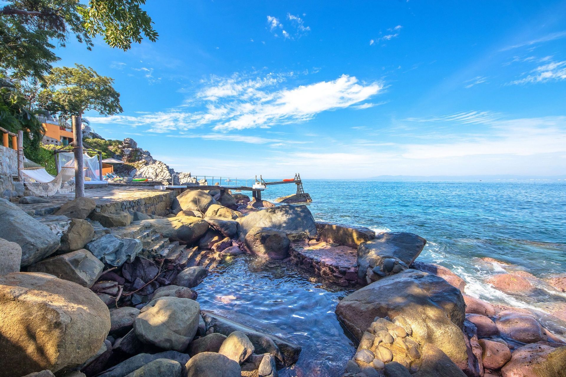 a view of the ocean from a rocky shoreline on a sunny day