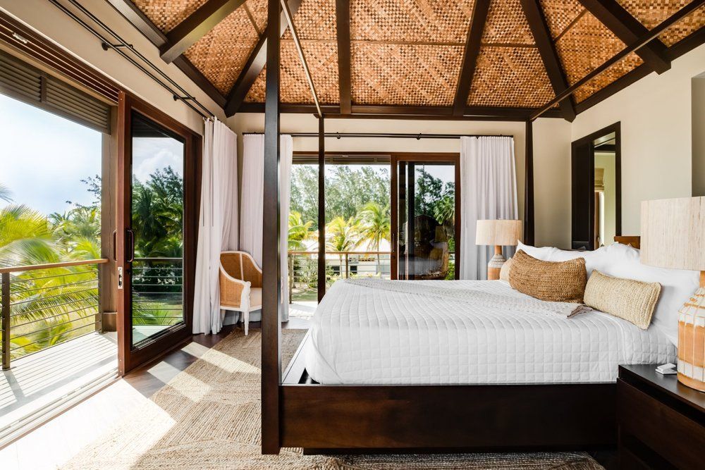 a bedroom with a four poster bed, sliding glass doors and a wicker ceiling