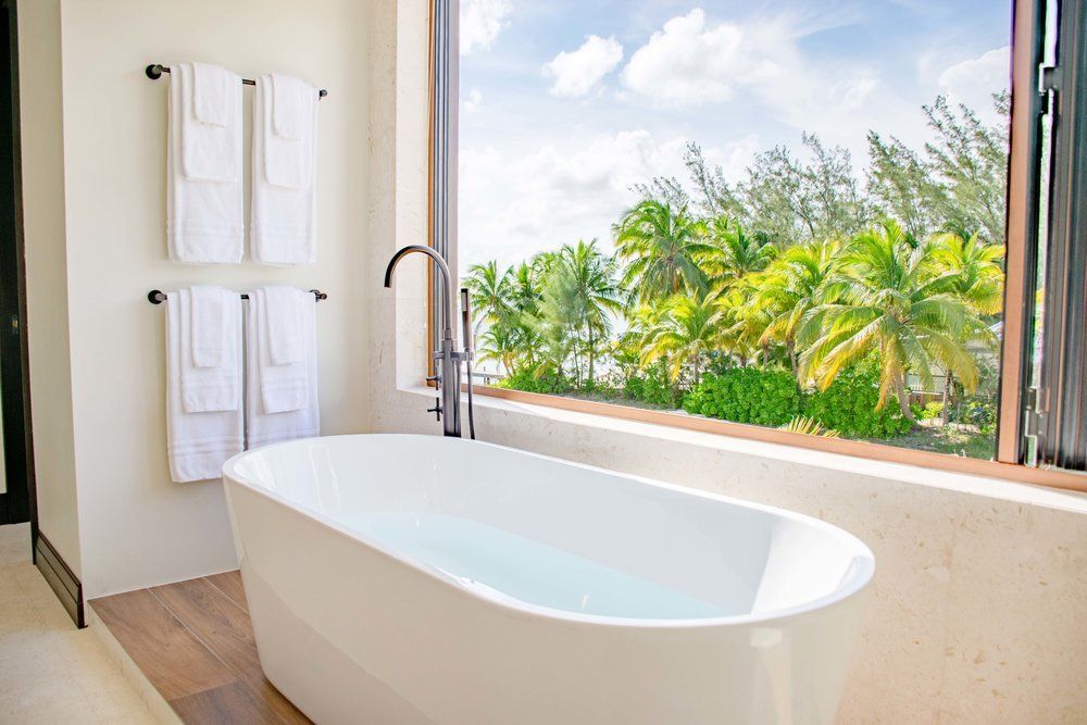 a bathroom with a bathtub and a window with a view of palm trees