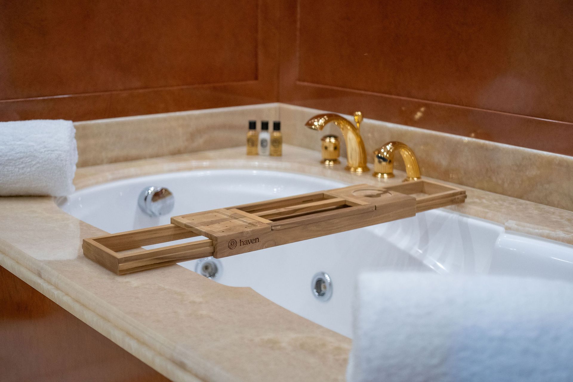 a bathtub with a wooden tray on the side of it in a bathroom
