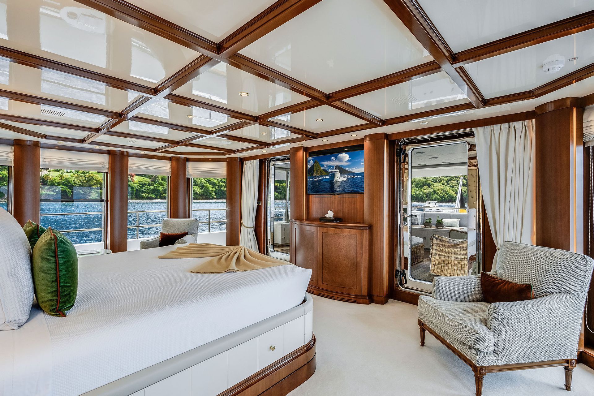 a bedroom on a yacht with a large bed, chair and television