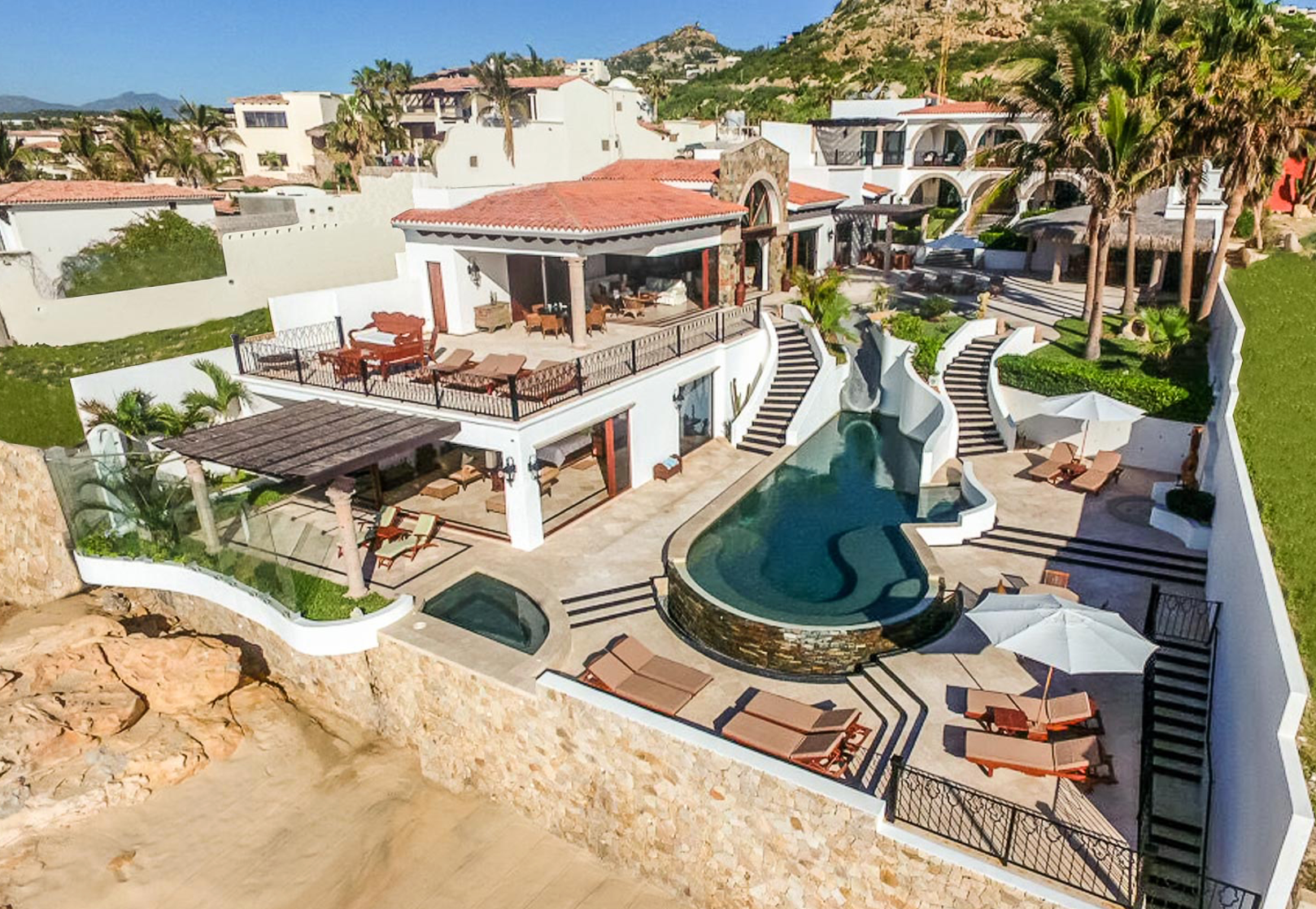 an aerial view of a large house with a swimming pool surrounded by palm trees