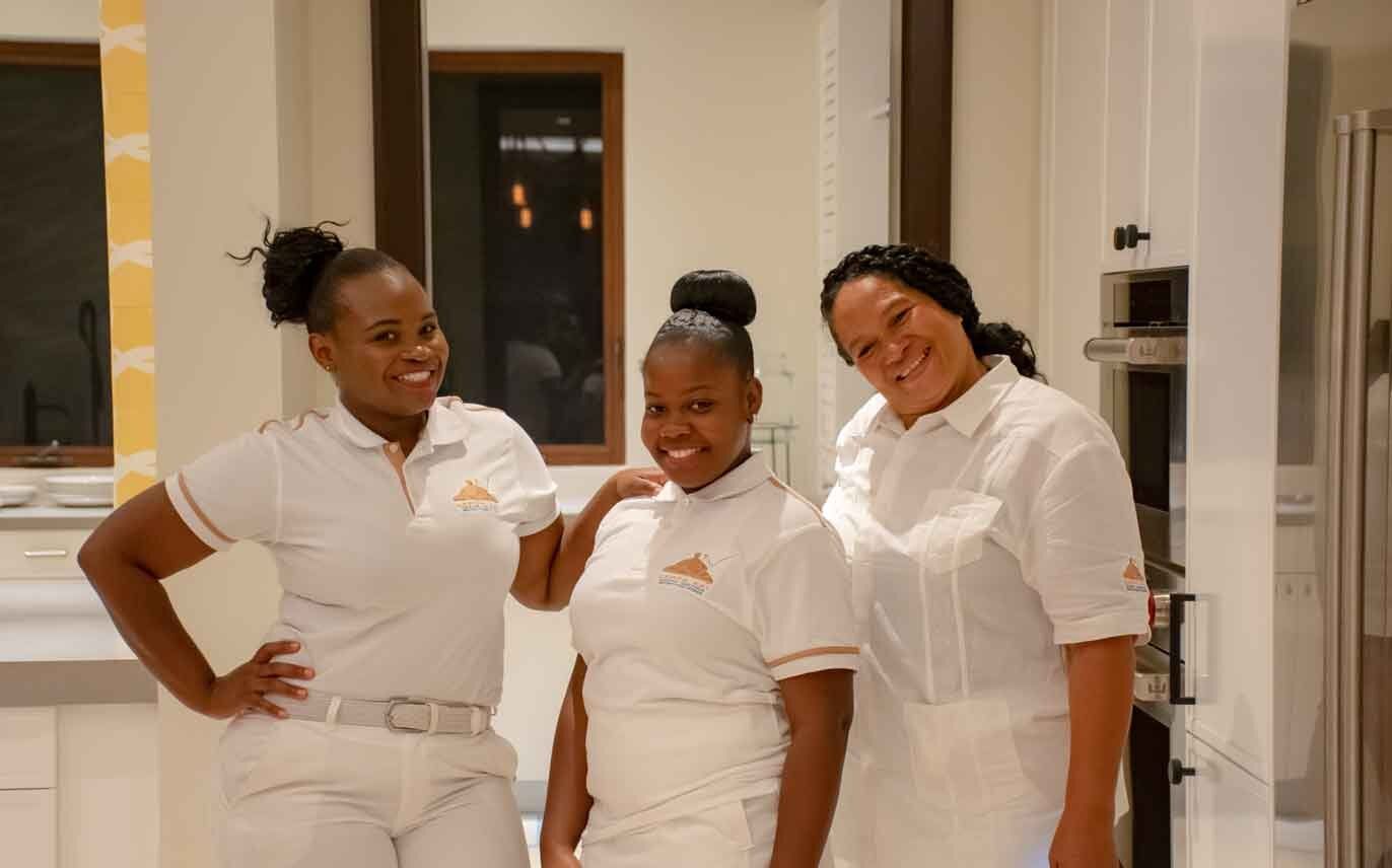 three women in white uniforms are posing for a picture in a kitchen