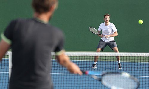 two men are playing tennis on a tennis court