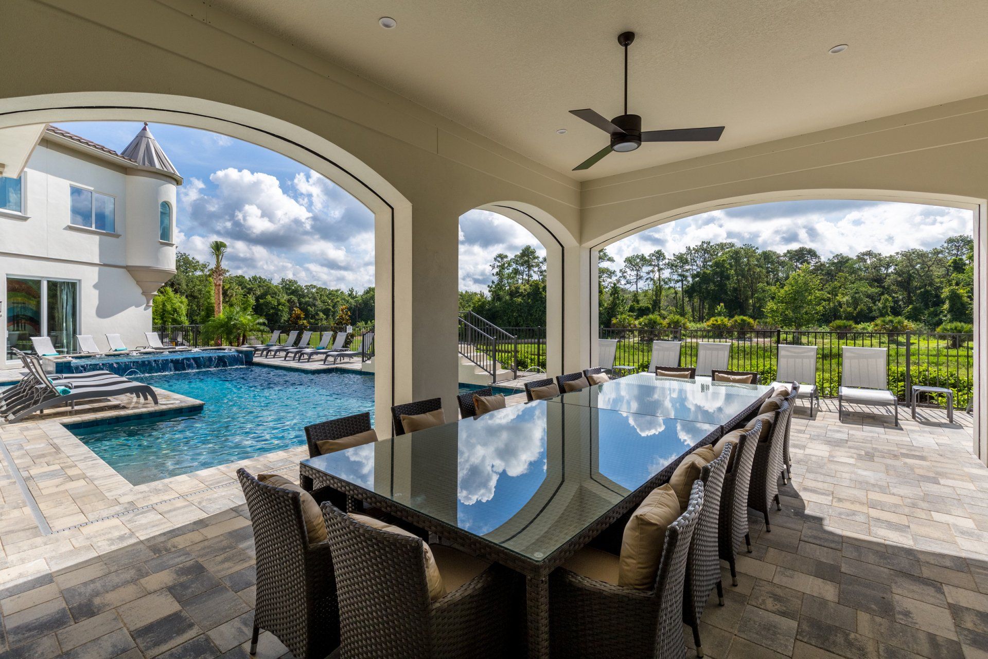 there is a large table and chairs on the patio with a pool in the background