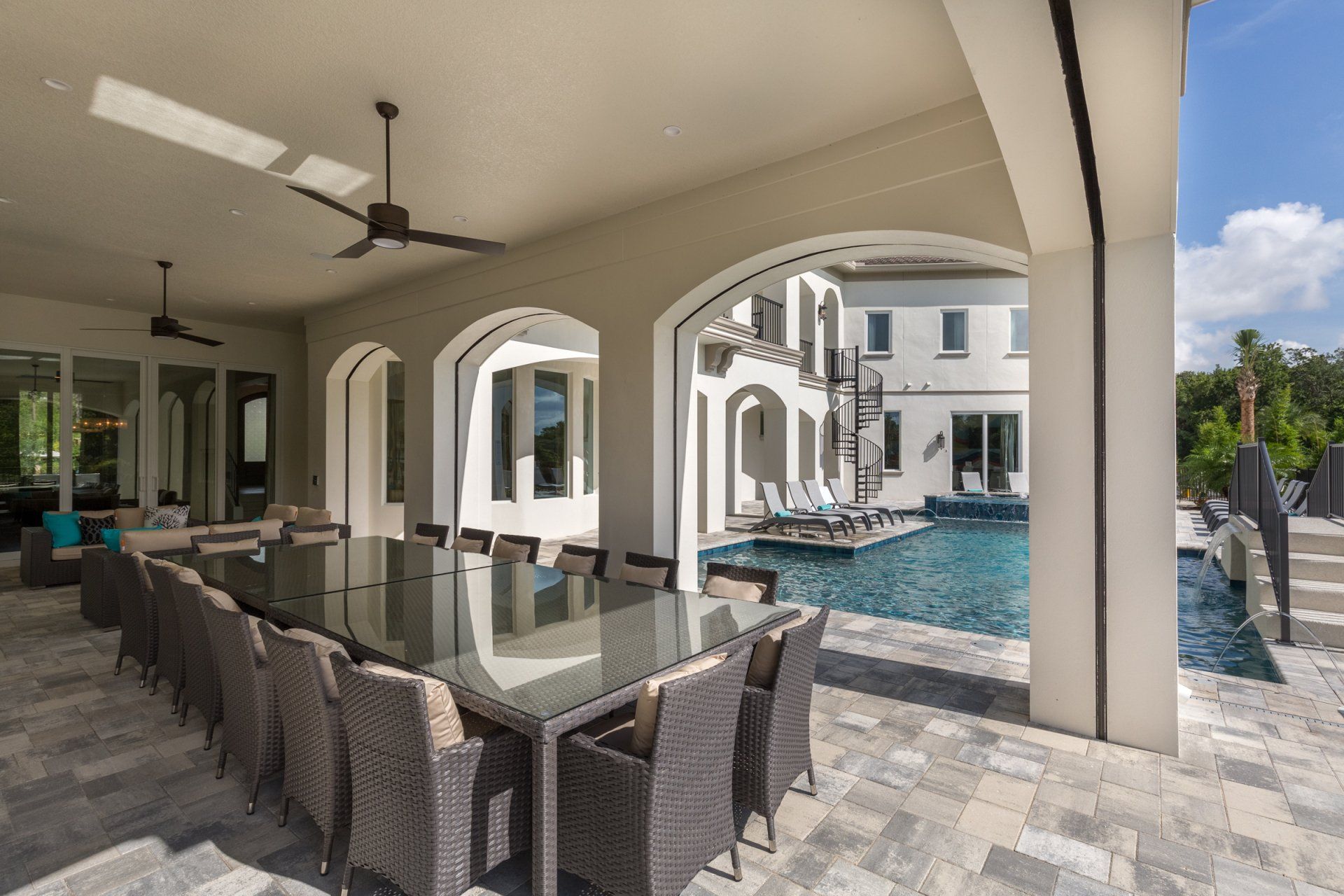 a large patio with a table and chairs next to a pool