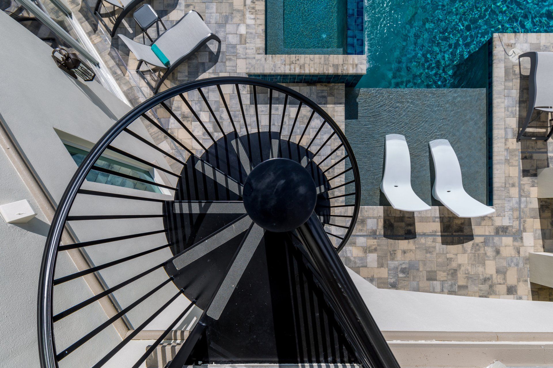 an aerial view of a spiral staircase leading to a swimming pool