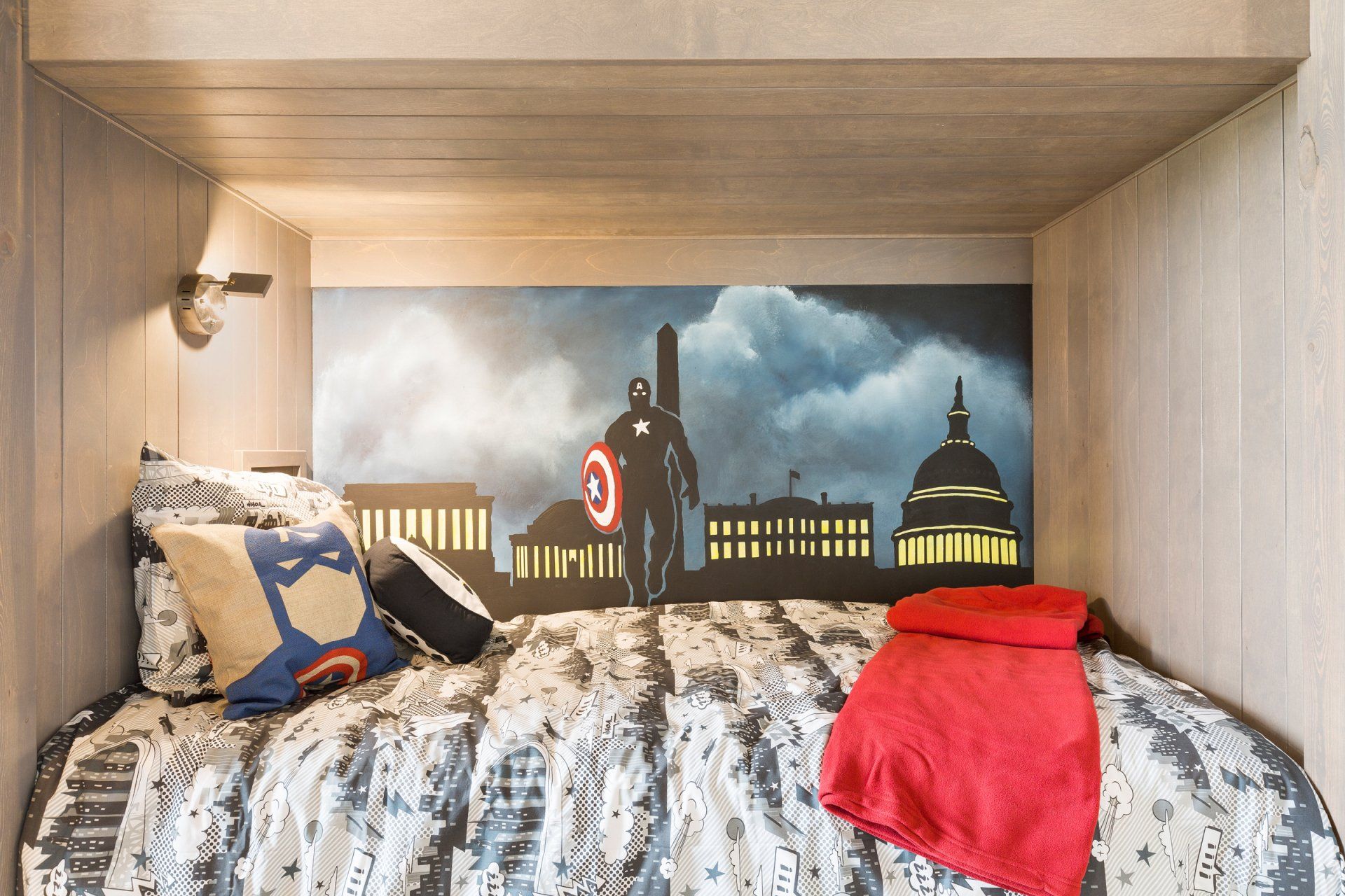 a bed with a superhero mural on the wall above it